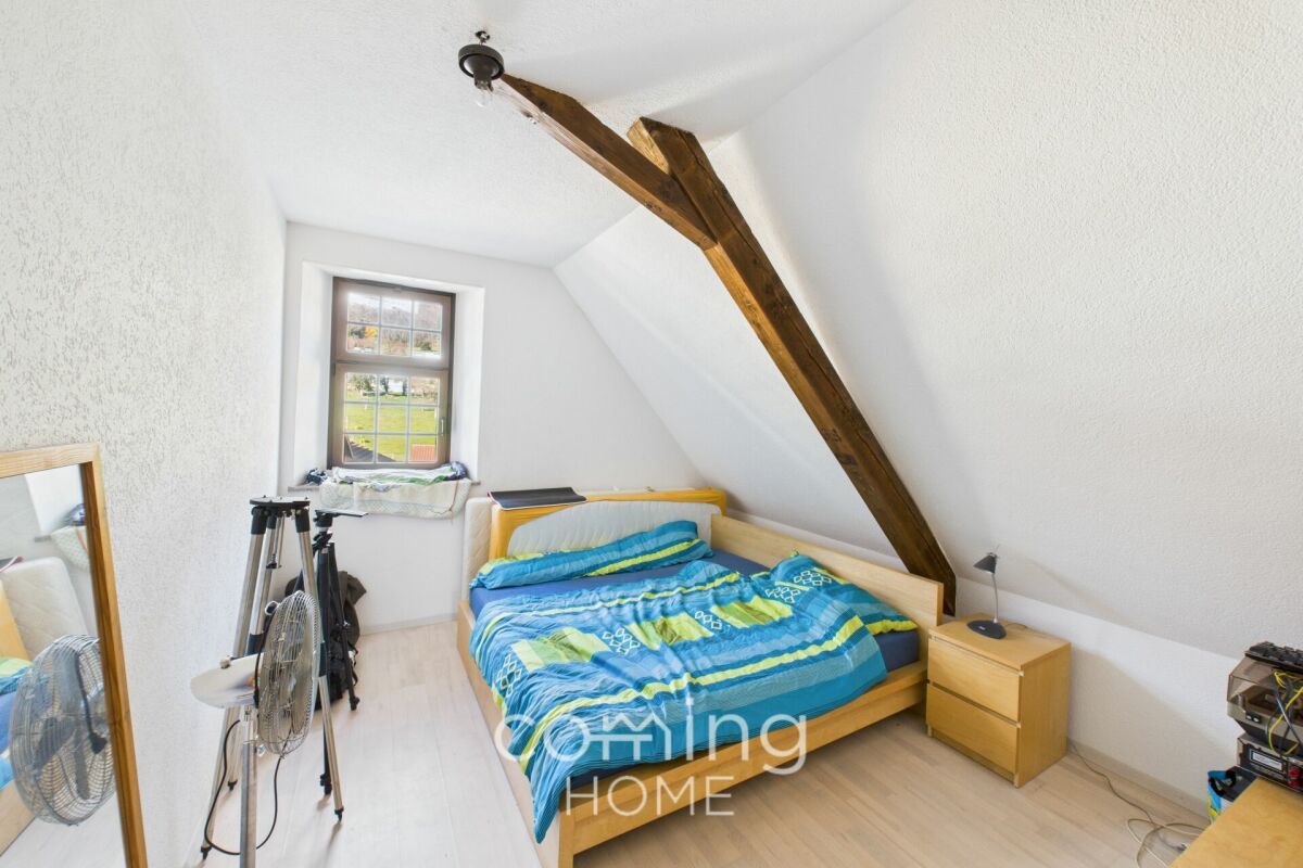 Dachgeschoss-Schlafzimmer mit sichtbarem Holzbalken