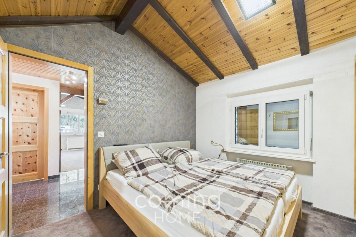 Schlafzimmer mit Holzdecke und Musterwand