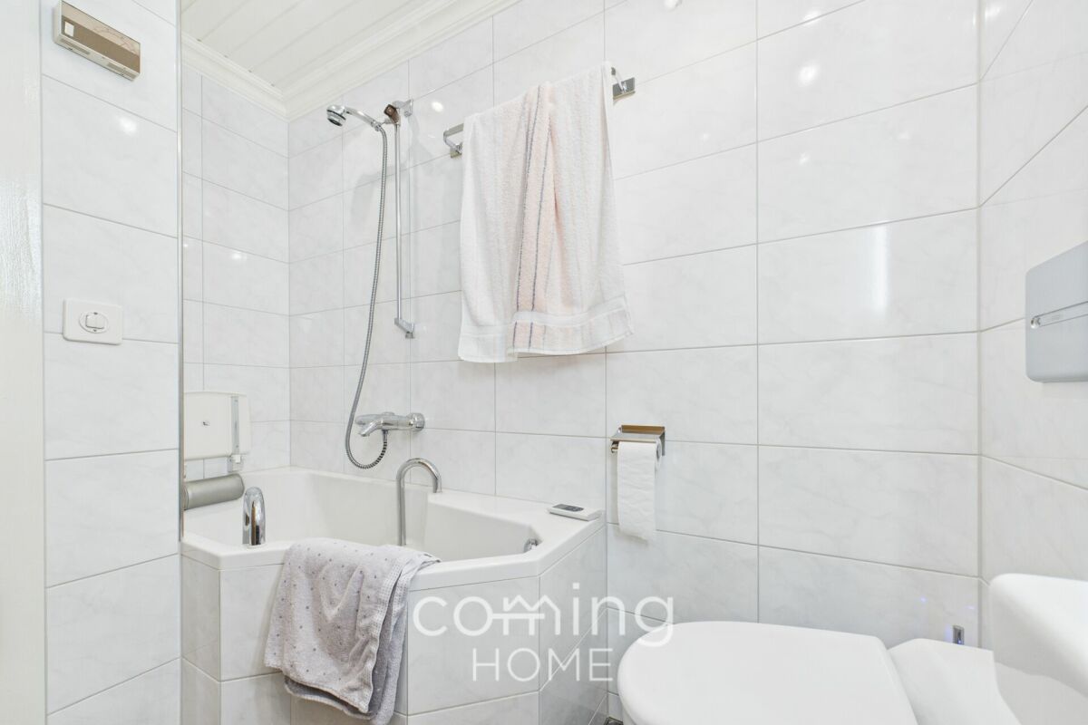 Helles Badezimmer mit Badewanne und weiß gefliesten Wänden