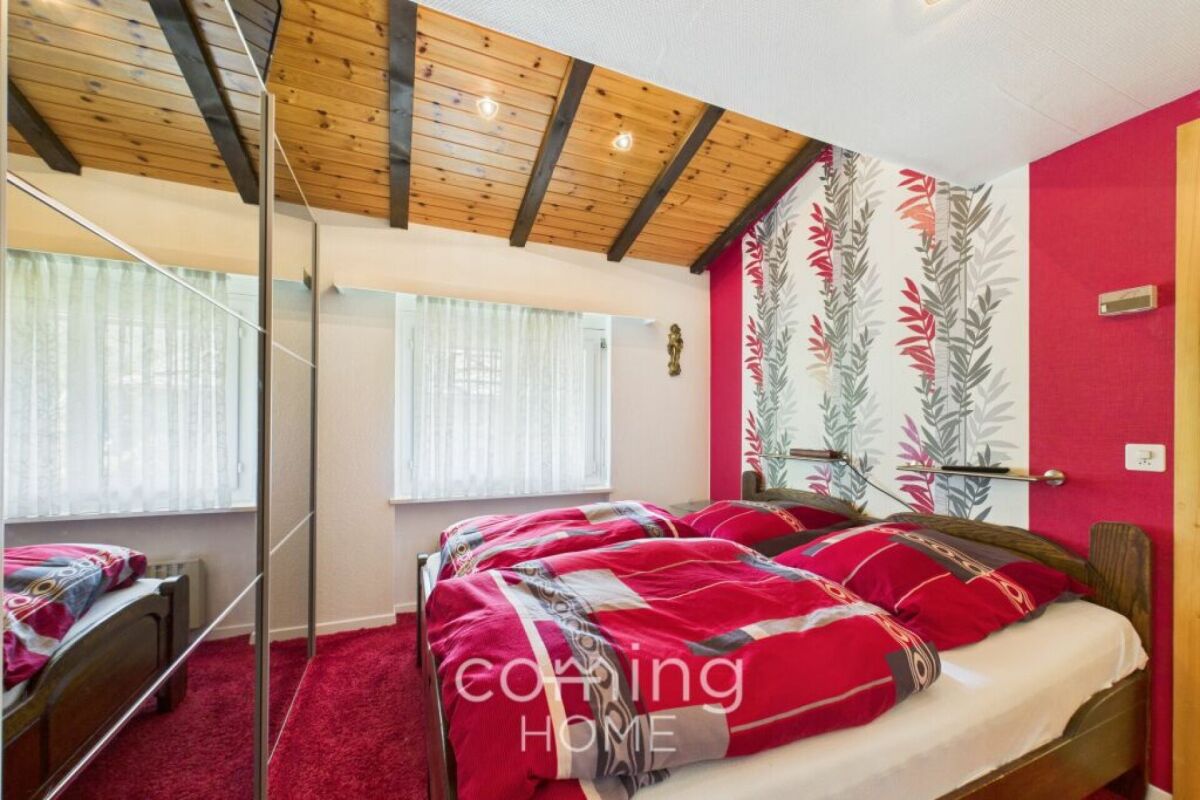 Schlafzimmer mit auffälliger Tapete und Holzdecke