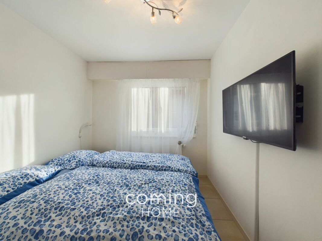 Kleines Schlafzimmer mit Doppelbett und Wandfernseher