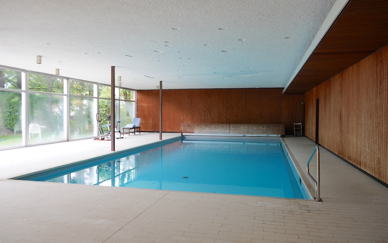 Innenpool mit Holzverkleidung und großen Fensterfronten