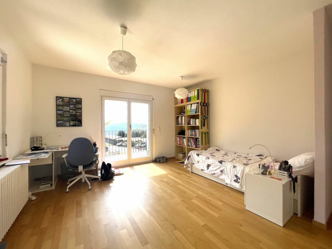 Helles Schlafzimmer mit Arbeitsbereich und Balkonblick