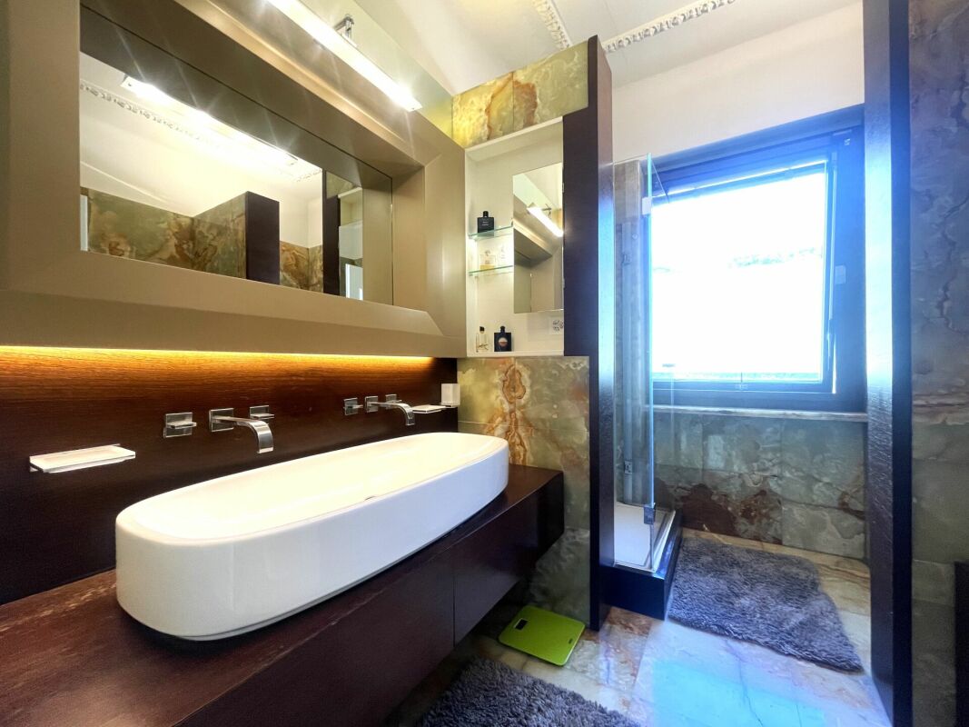 Luxuriöses Badezimmer mit Naturstein und großer Spiegelfront