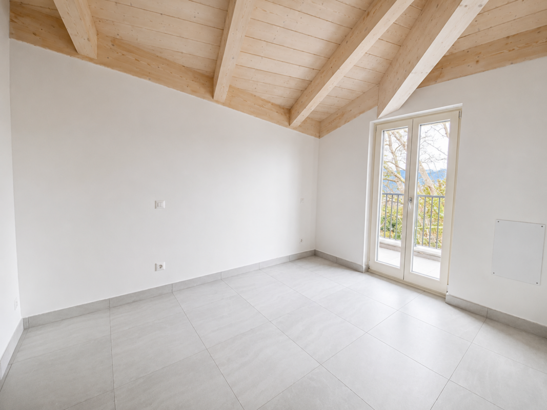 Heller leerer Raum mit Balkon und Holzbalkendecke