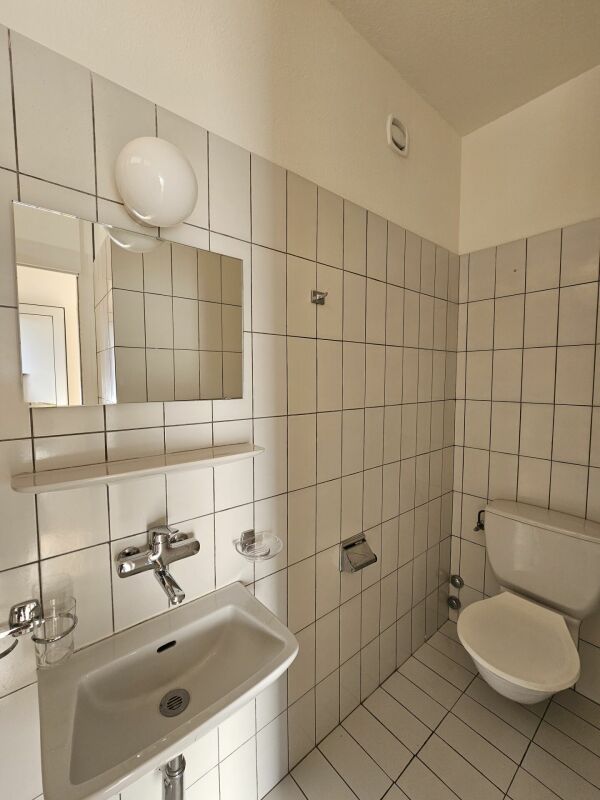 Gäste-WC mit weiß gefliesten Wänden