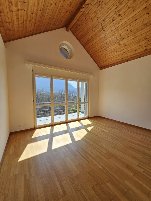 Heller leerer Raum mit Holzdecke und Balkonblick