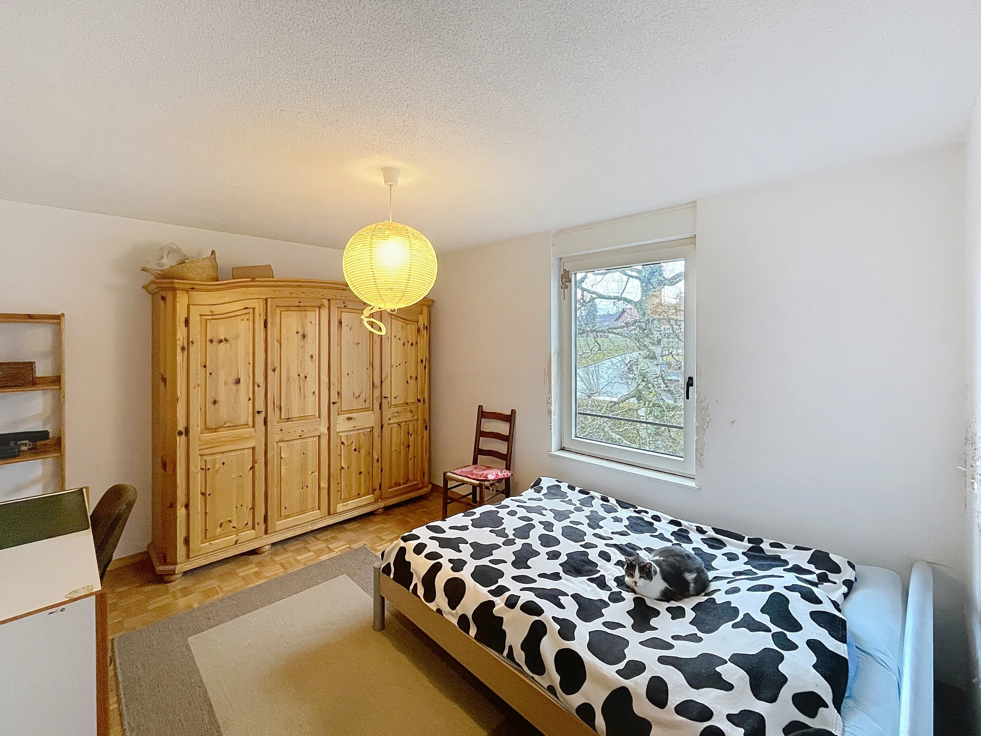 Helles Schlafzimmer mit Holzschrank und Fensterblick
