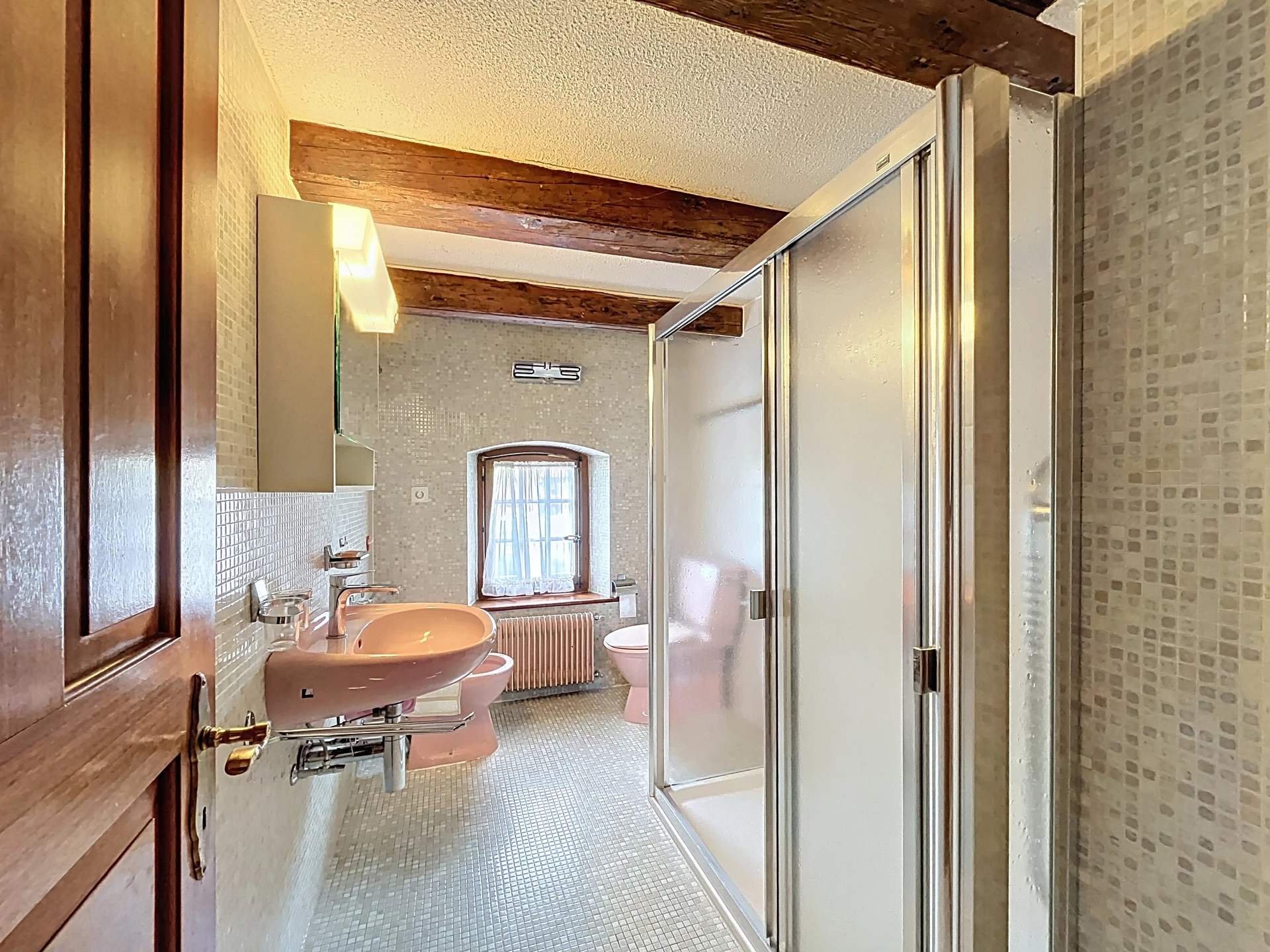 Badezimmer mit Mosaikfliesen und Holzbalken