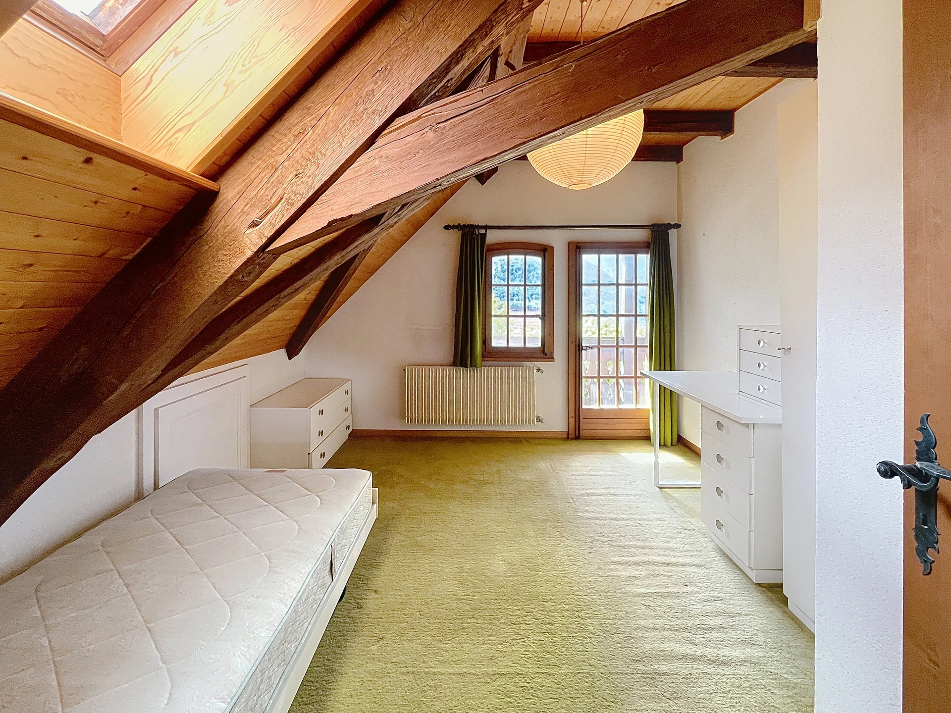 Dachgeschoss-Schlafzimmer mit sichtbaren Holzbalken