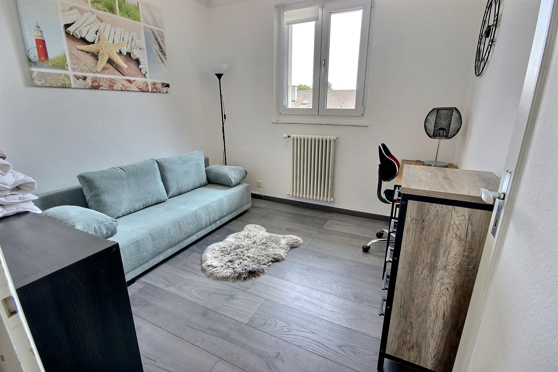Kleines helles Zimmer mit Sofa und Schreibtisch