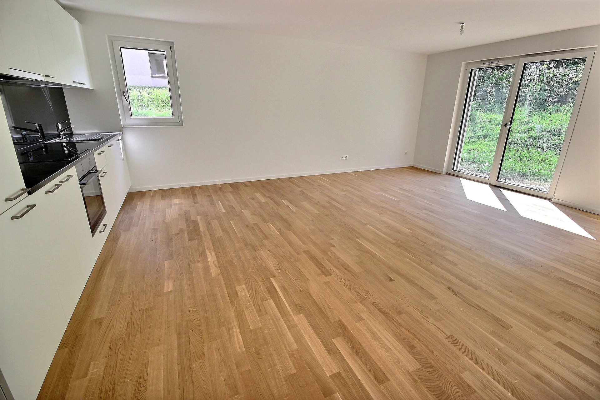 Heller Wohnraum mit offener Küche und Gartenausblick