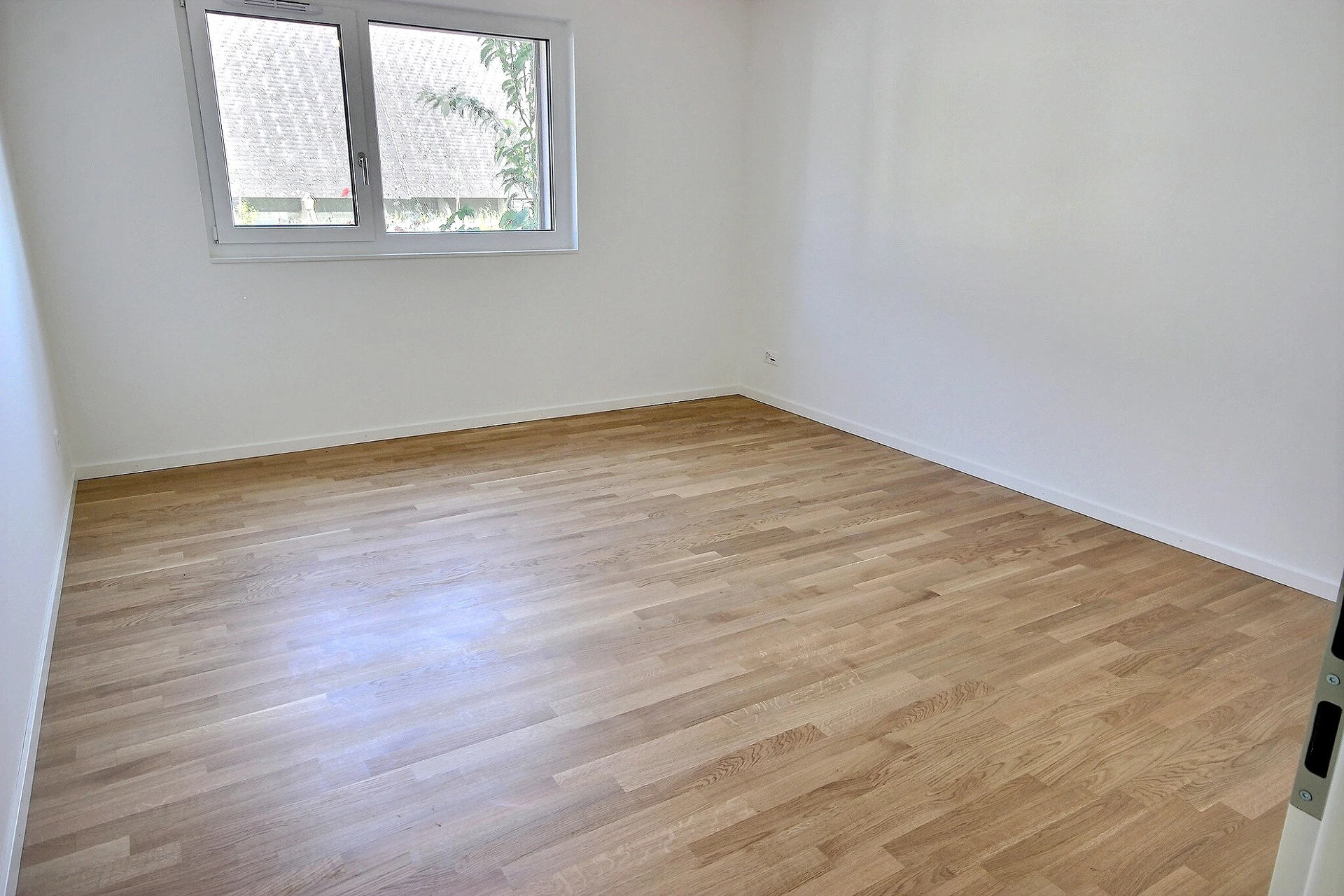 Leerer heller Raum mit Fenster und Holzfußboden