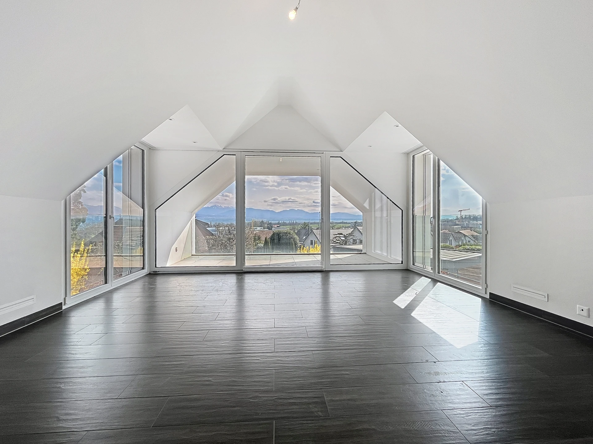 Leerer, lichtdurchfluteter Dachgeschossraum mit Panoramafenstern und Ausblick