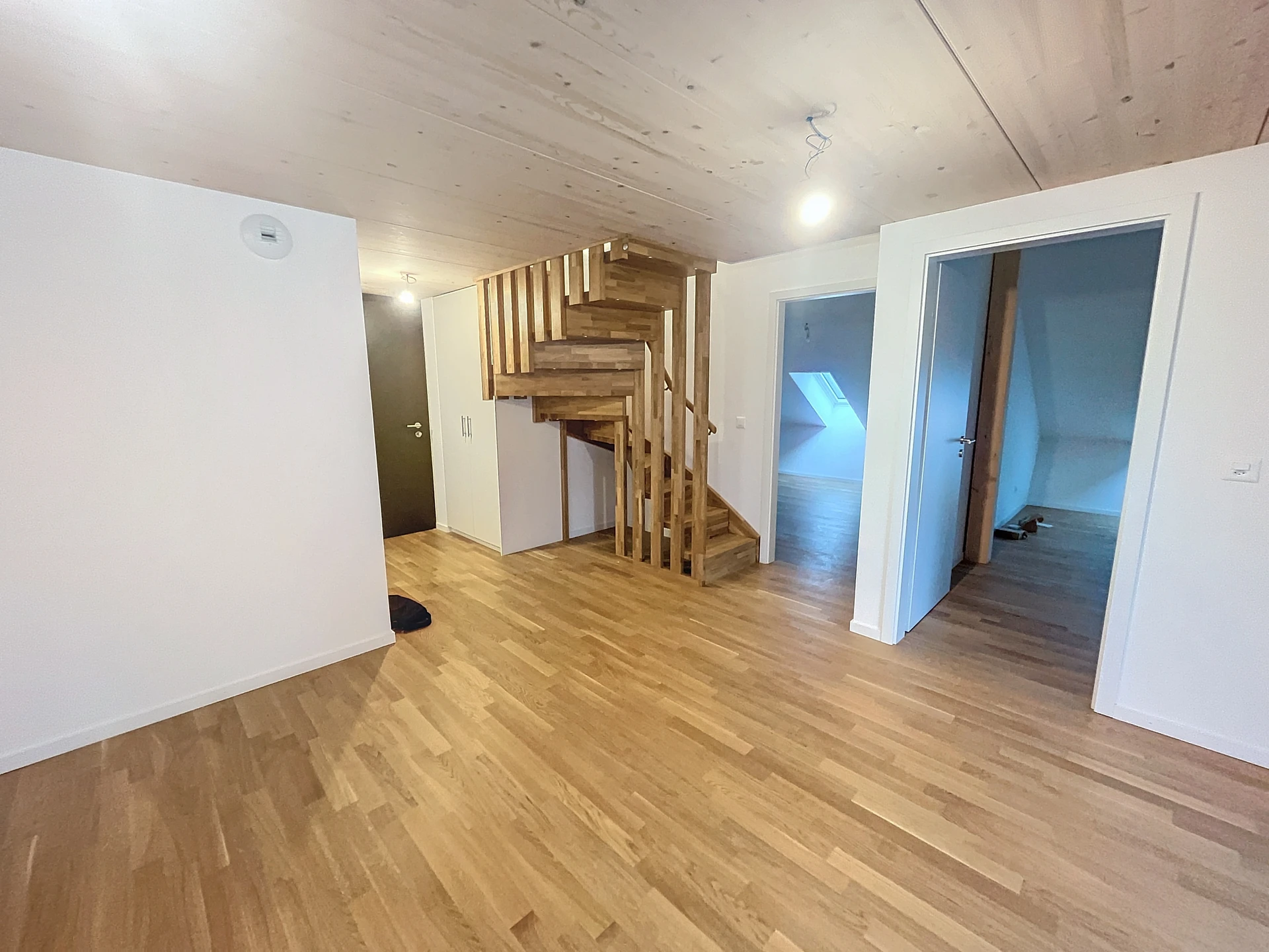 Modernisiertes Dachgeschosszimmer mit Holztreppe