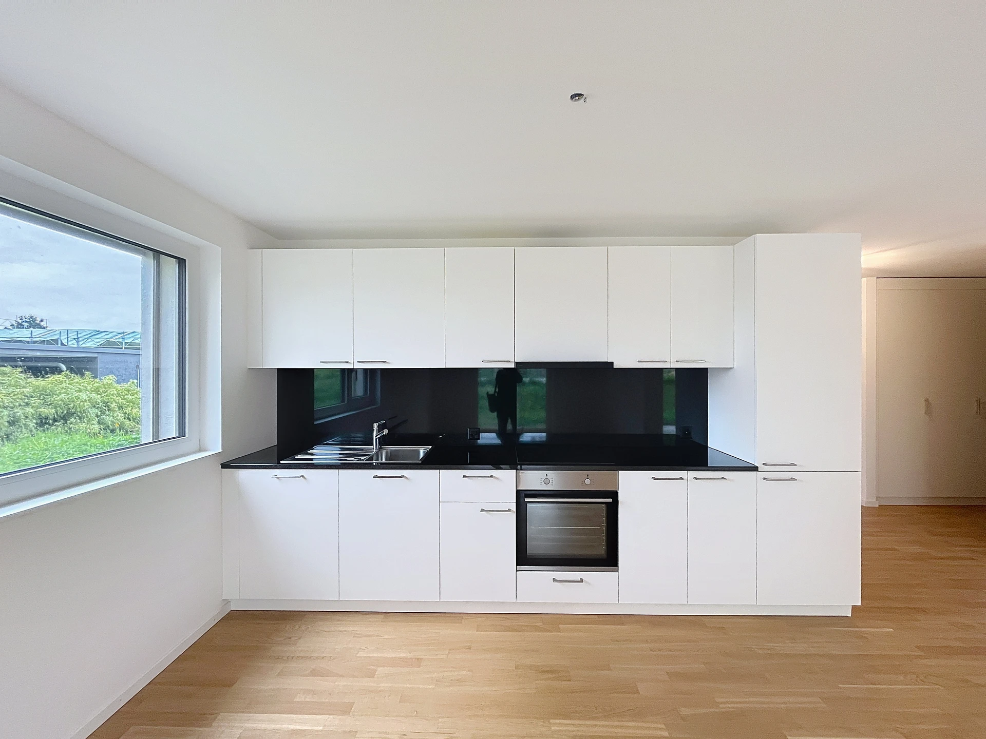 Helle, moderne Küche mit weißer Küchenzeile und schwarzer Rückwand