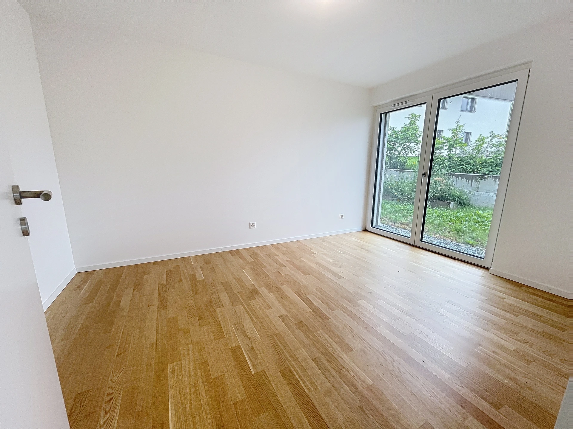Heller leerer Raum mit Holzparkett und Terrassentür