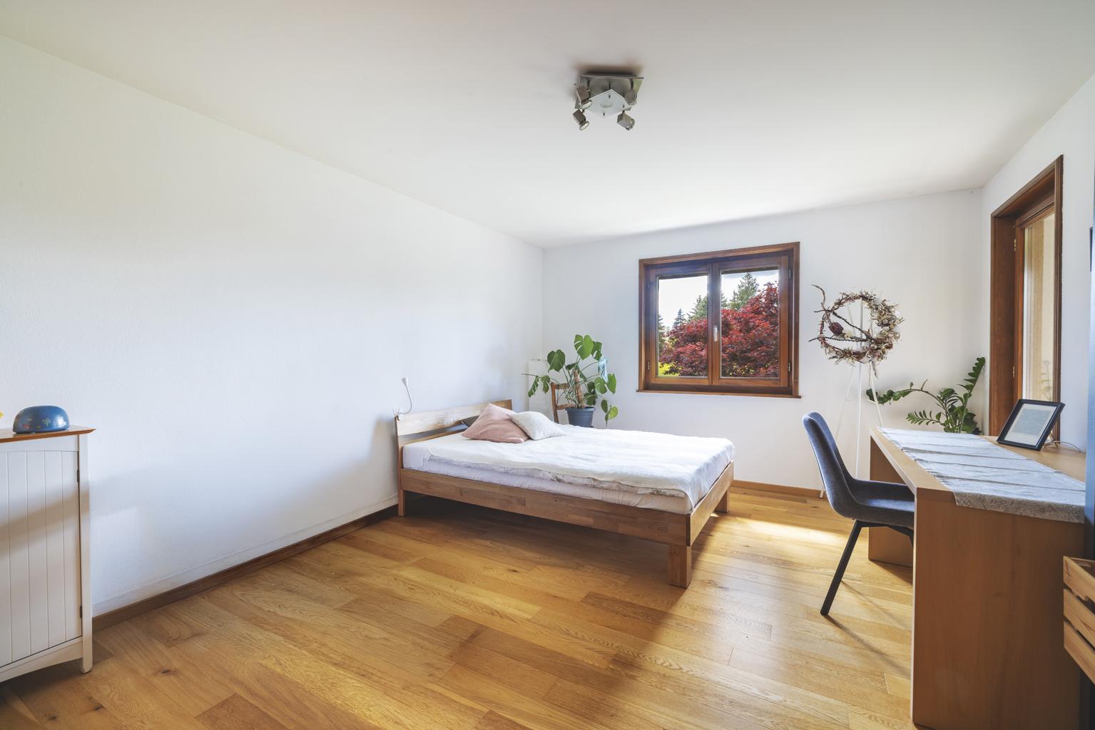 Helles Schlafzimmer mit Holzboden und Arbeitsbereich