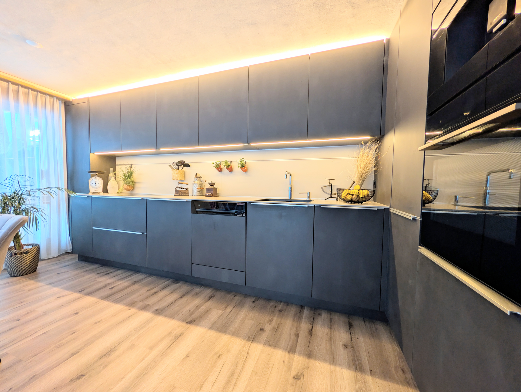Moderne Küche mit dunklen Fronten und Holzboden