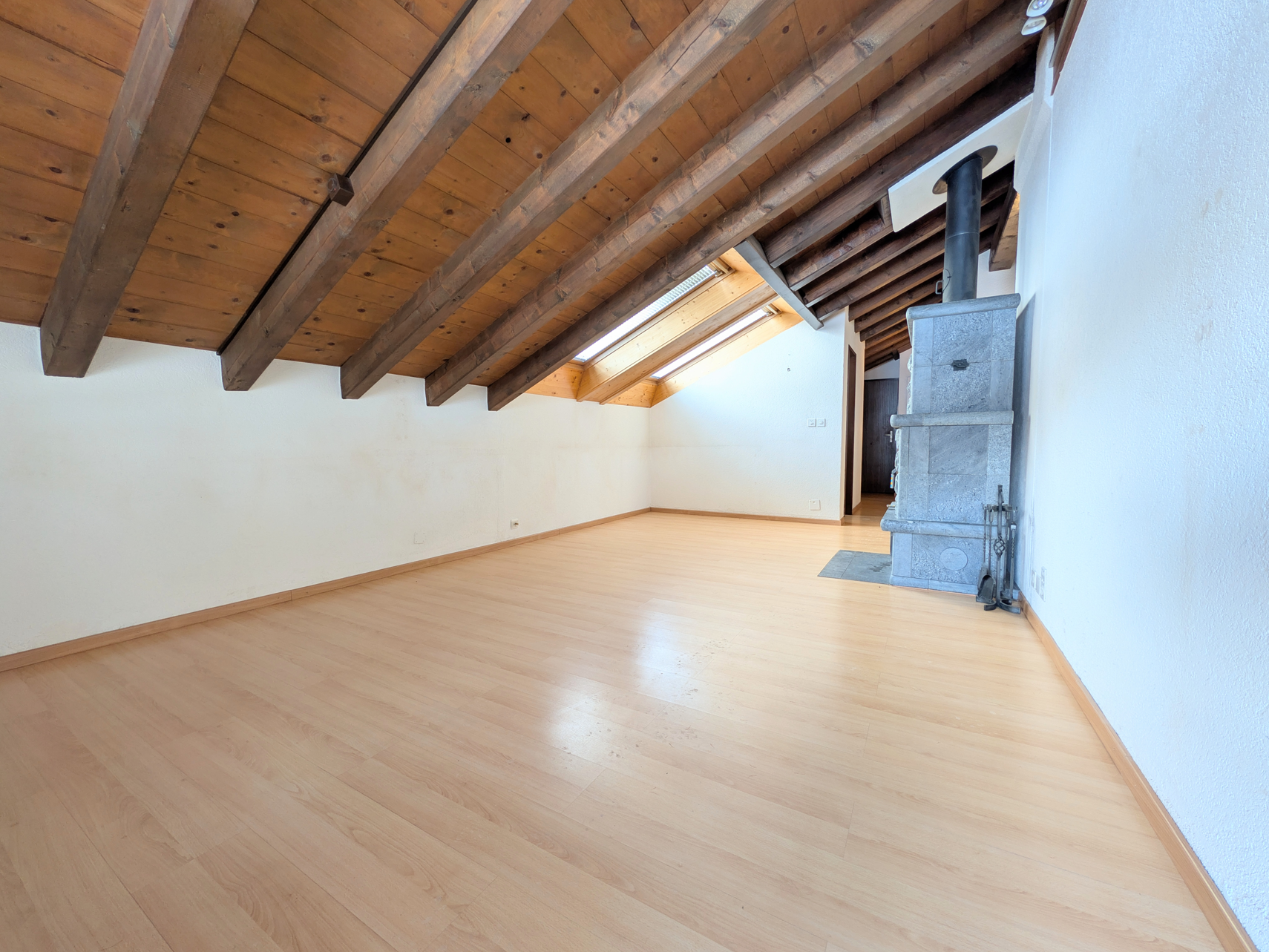 Dachgeschosszimmer mit Holzbalken und Ofen
