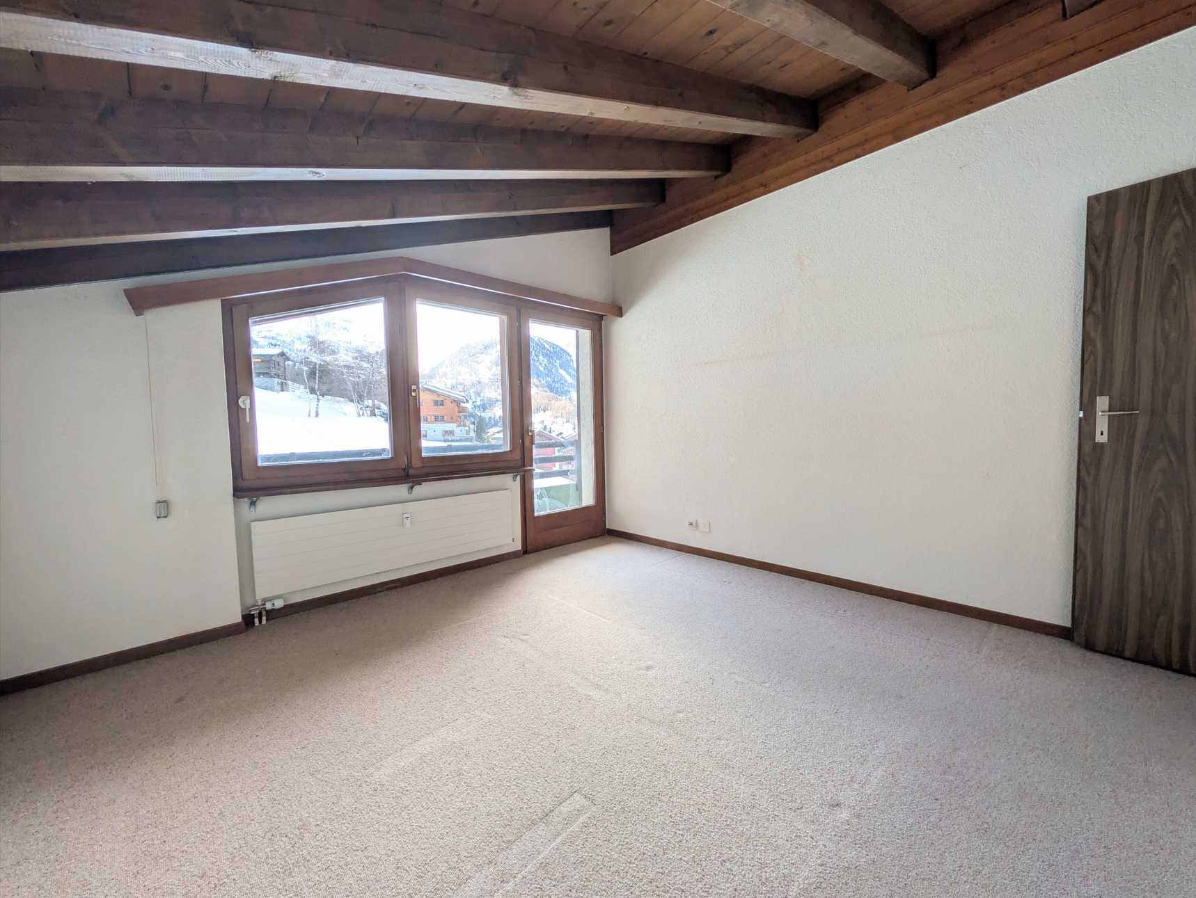 Leeres Zimmer mit Holzbalkendecke und Bergblick
