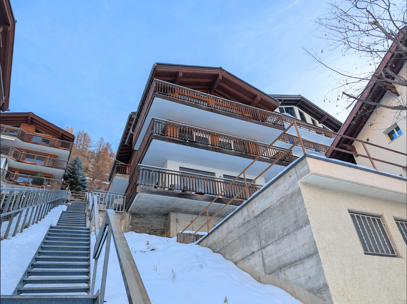 Alpine-Mehrfamilienhaus mit Balkonen und Außentreppe