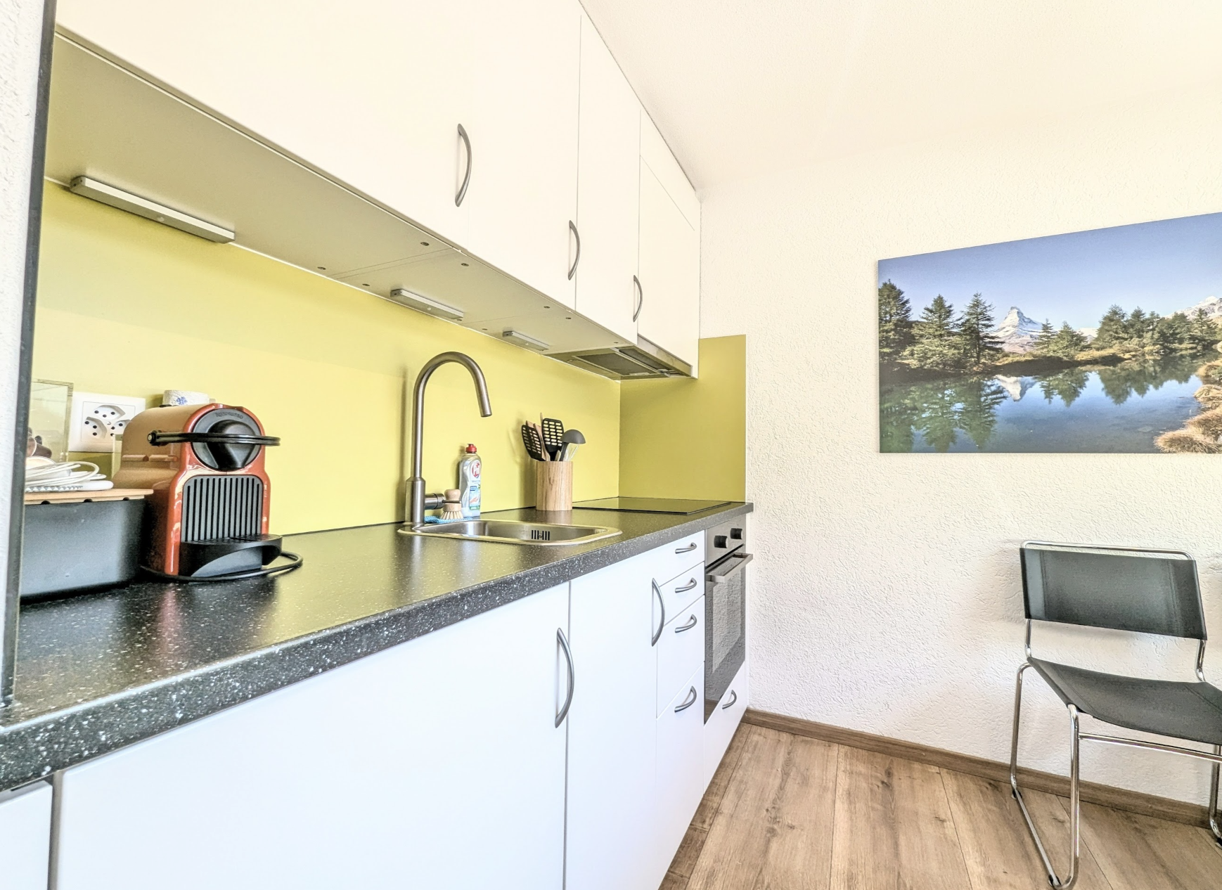 Kleine moderne Küchenzeile mit gelber Rückwand