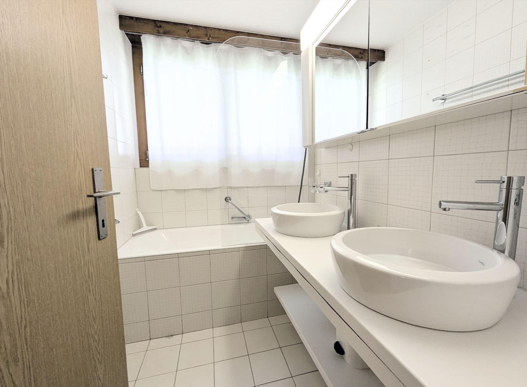 Helles Badezimmer mit Doppelwaschbecken und Wanne