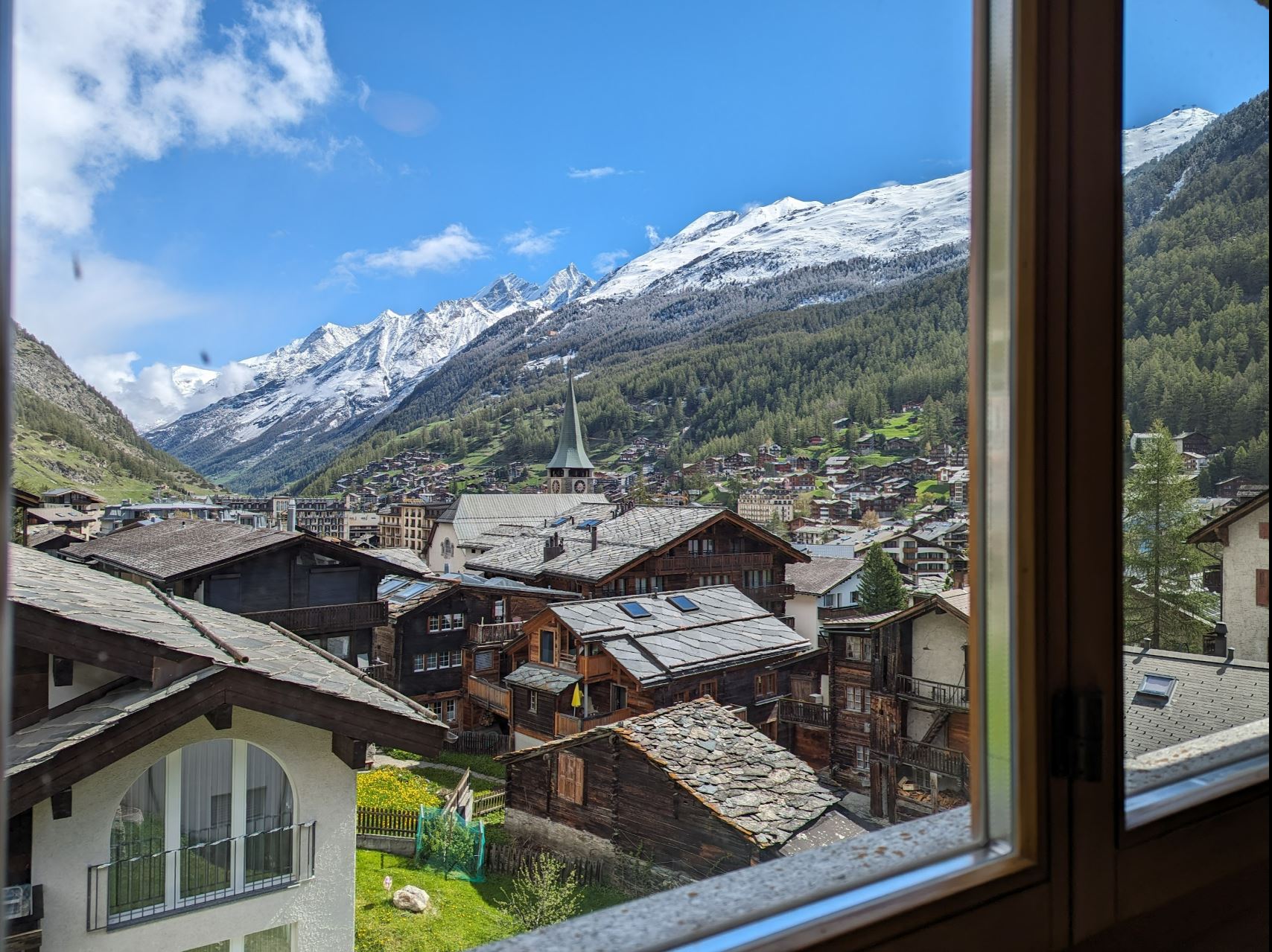 Alpenort mit Bergpanorama aus dem Fenster