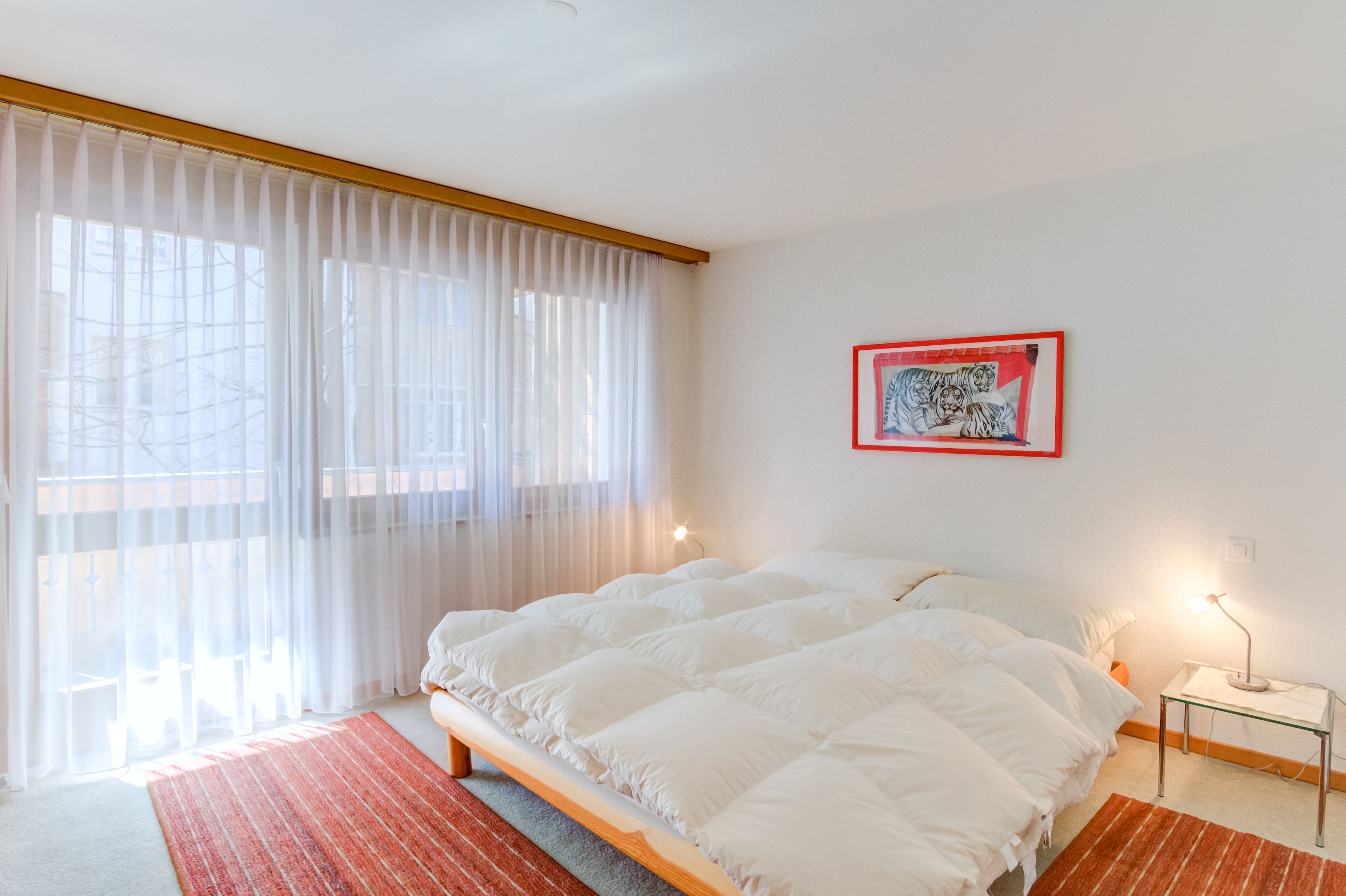 Helles Schlafzimmer mit großem Fenster und minimalistischer Einrichtung