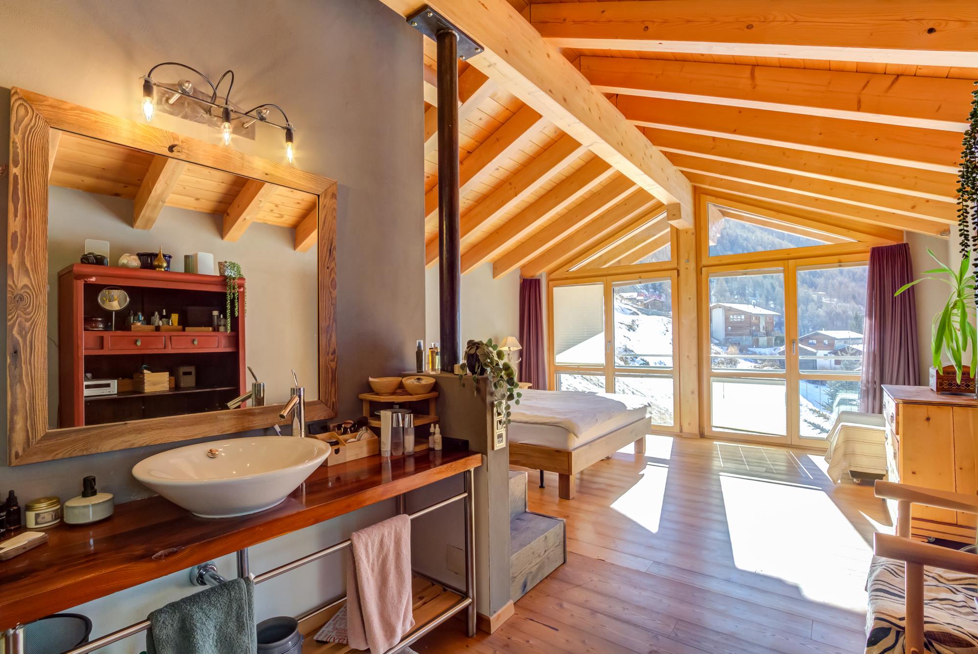 Helles Schlafzimmer mit Badbereich in alpiner Holzarchitektur