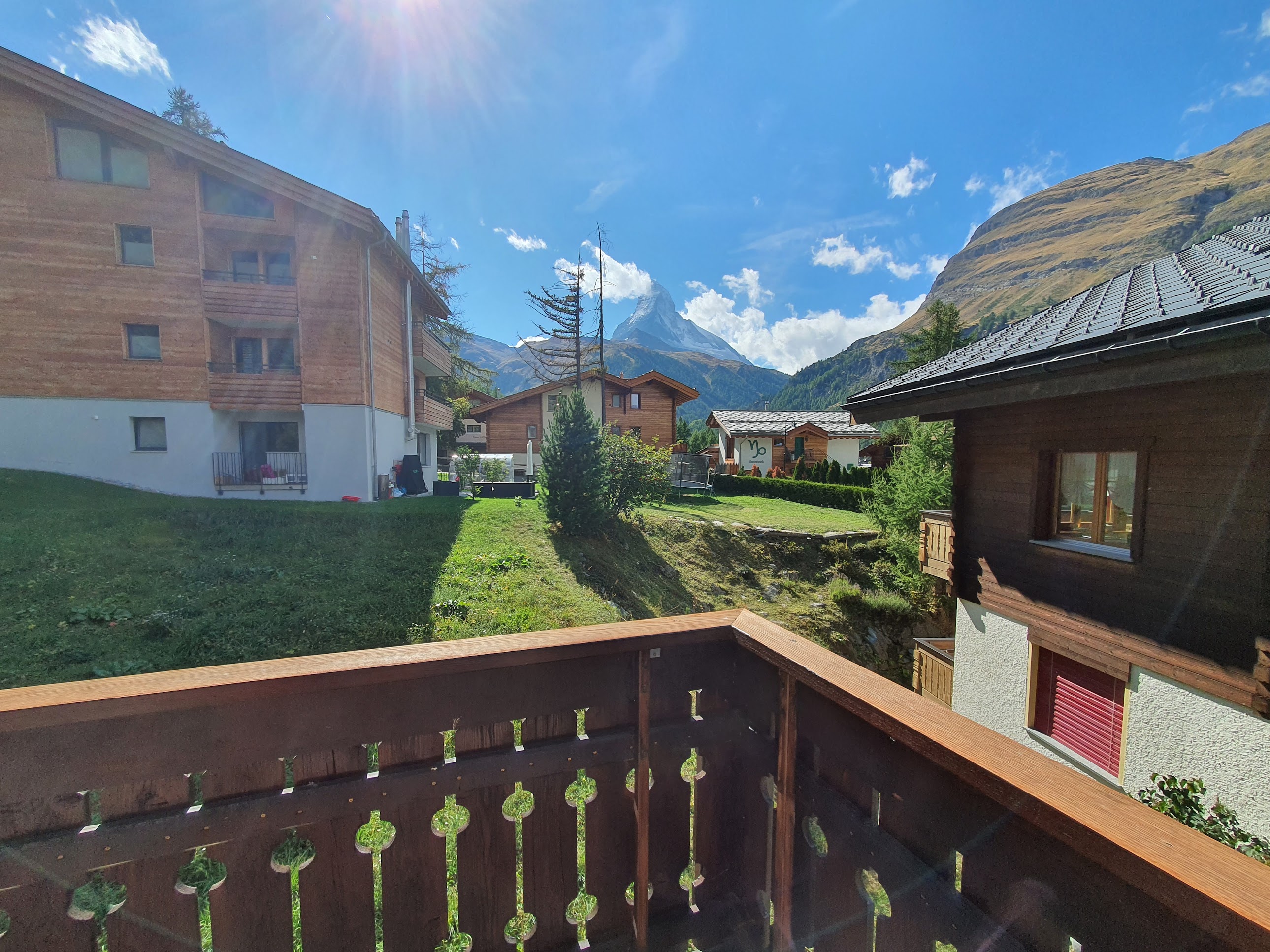 Balkonblick auf alpine Wohnhäuser und Berggipfel