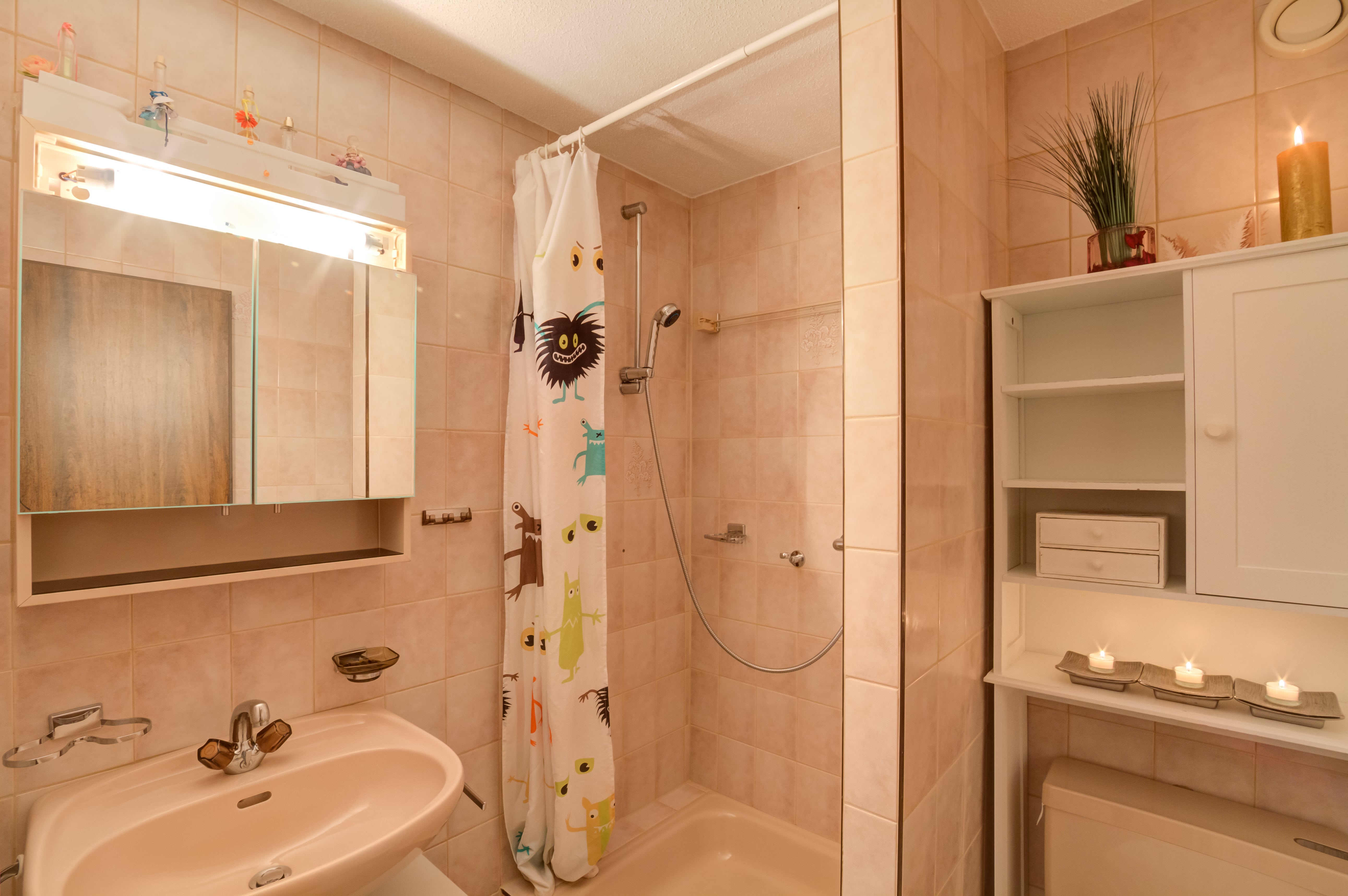 Badezimmer mit Duschbereich und Waschbecken