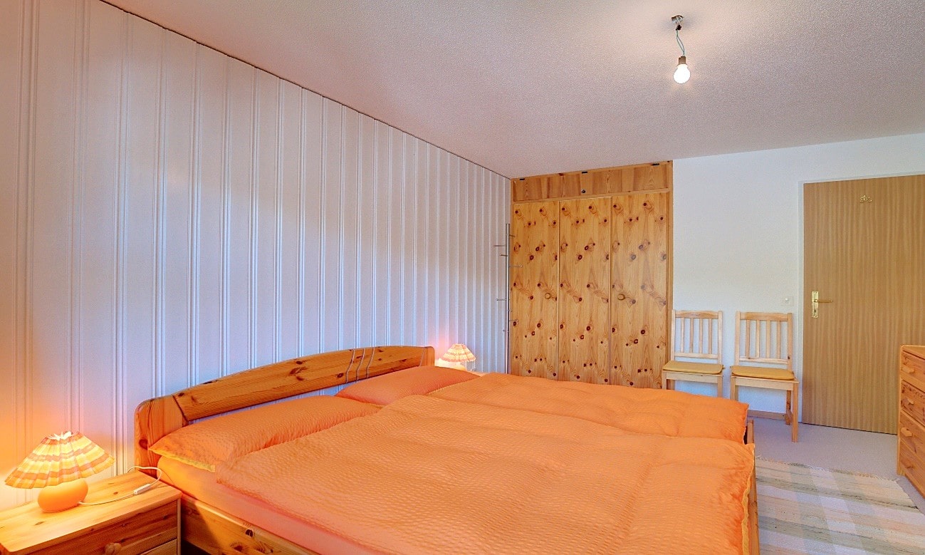 Schlafzimmer mit Holzmöbeln und orangefarbenem Bettzeug
