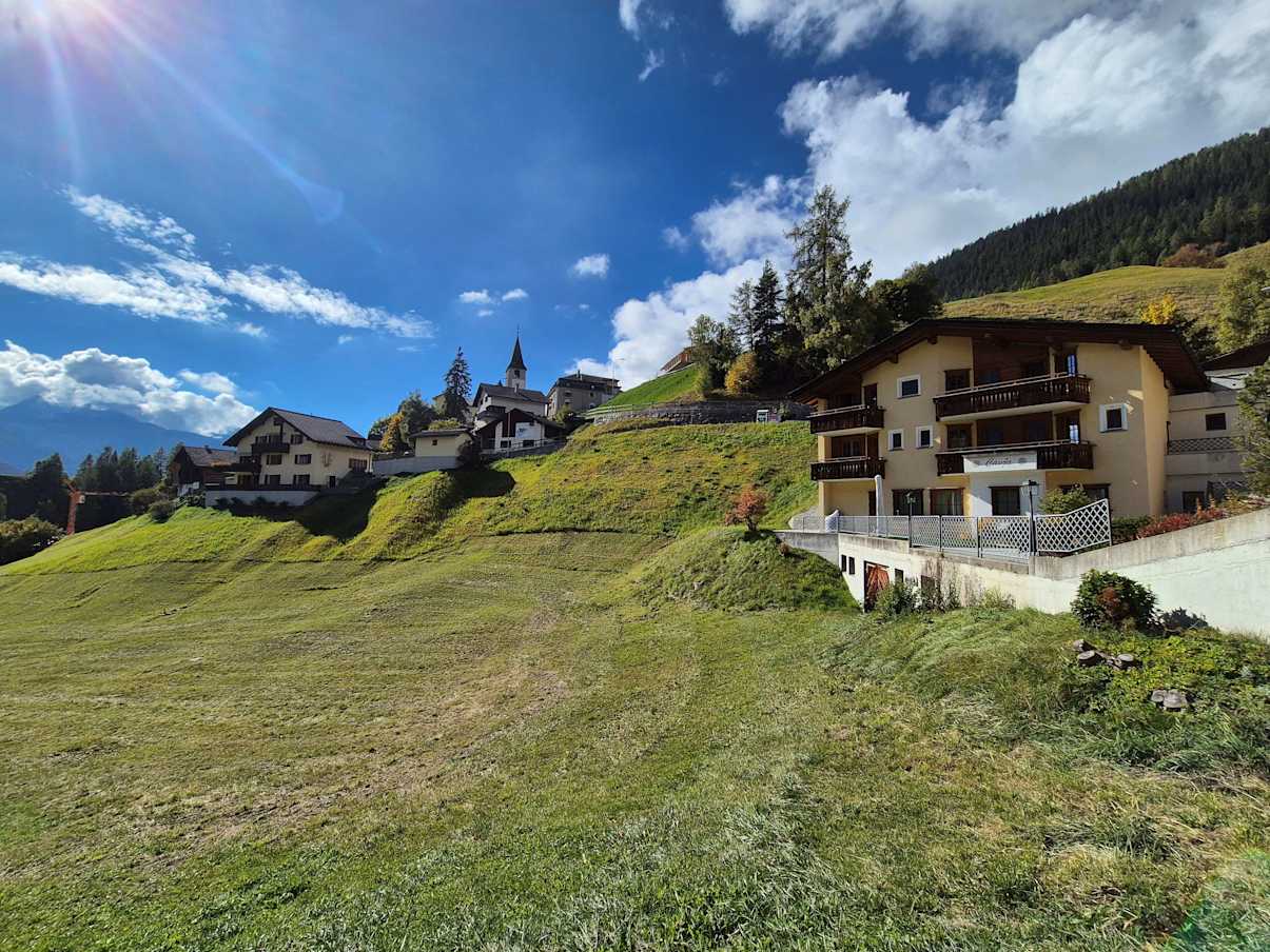 Bergdorf mit Wiesenhang und Wohnhäusern