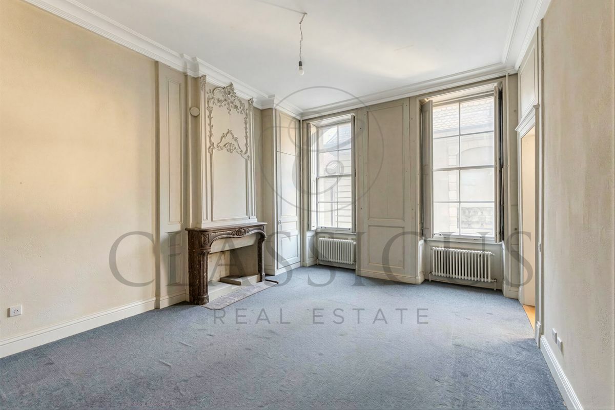 Eleganter Altbau-Raum mit Kamin und hohen Fenstern