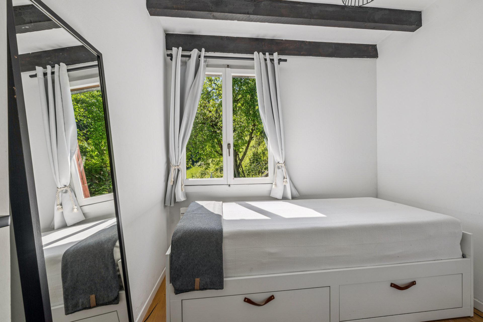 Helles Schlafzimmer mit Fensterblick ins Grüne
