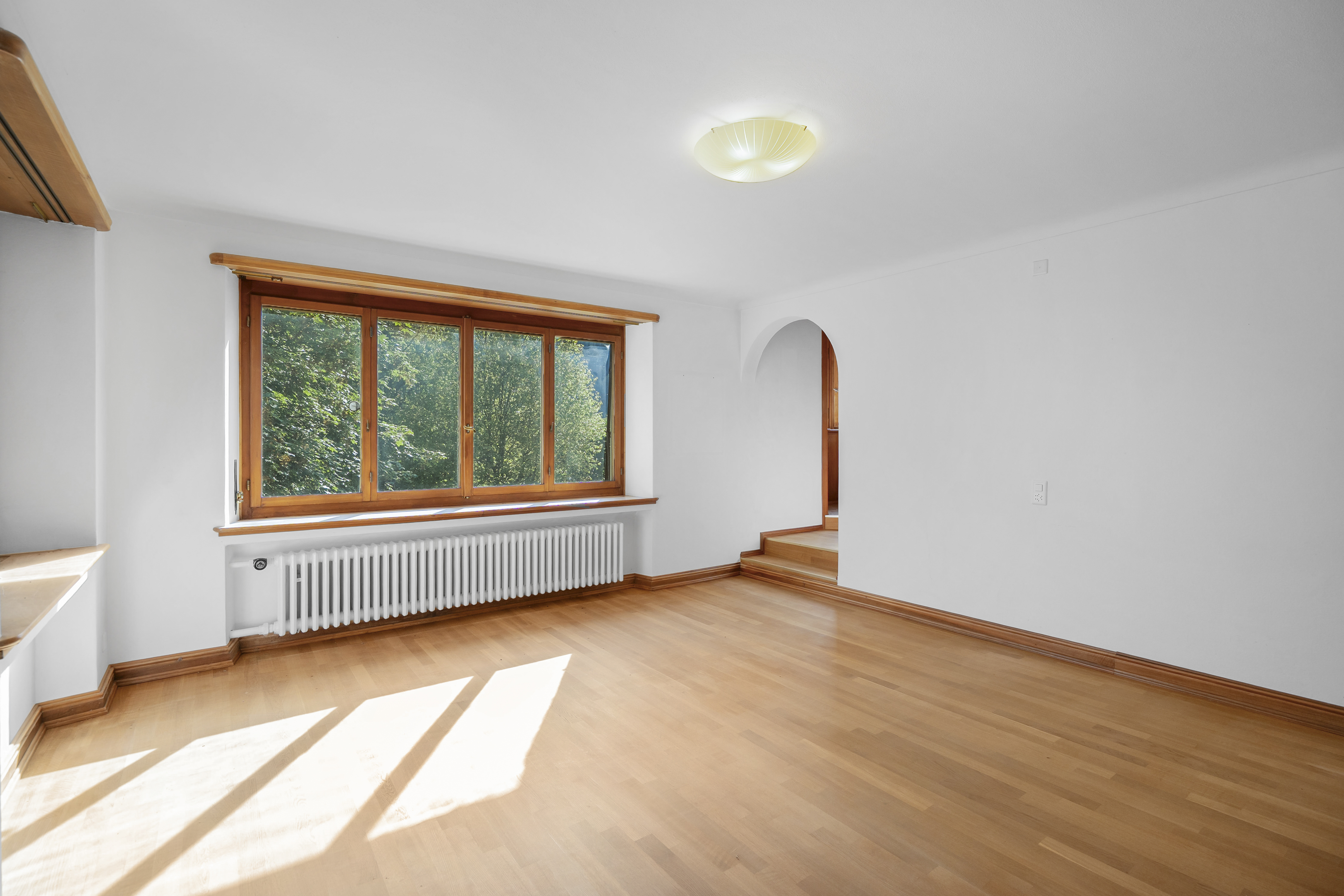 Heller leerer Wohnraum mit Holzfenstern und Parkett