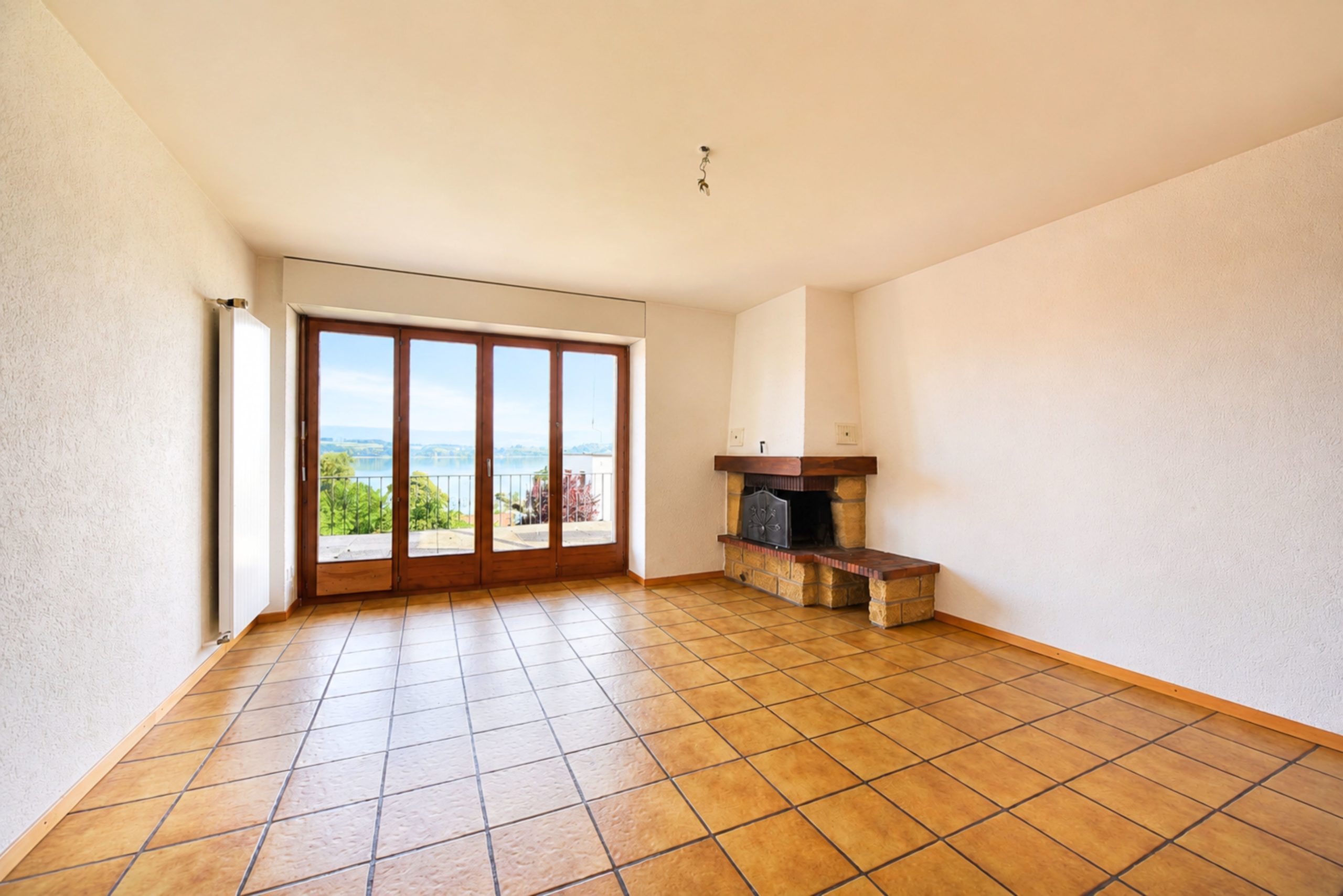 Leerer Wohnraum mit Kamin und Seeblick