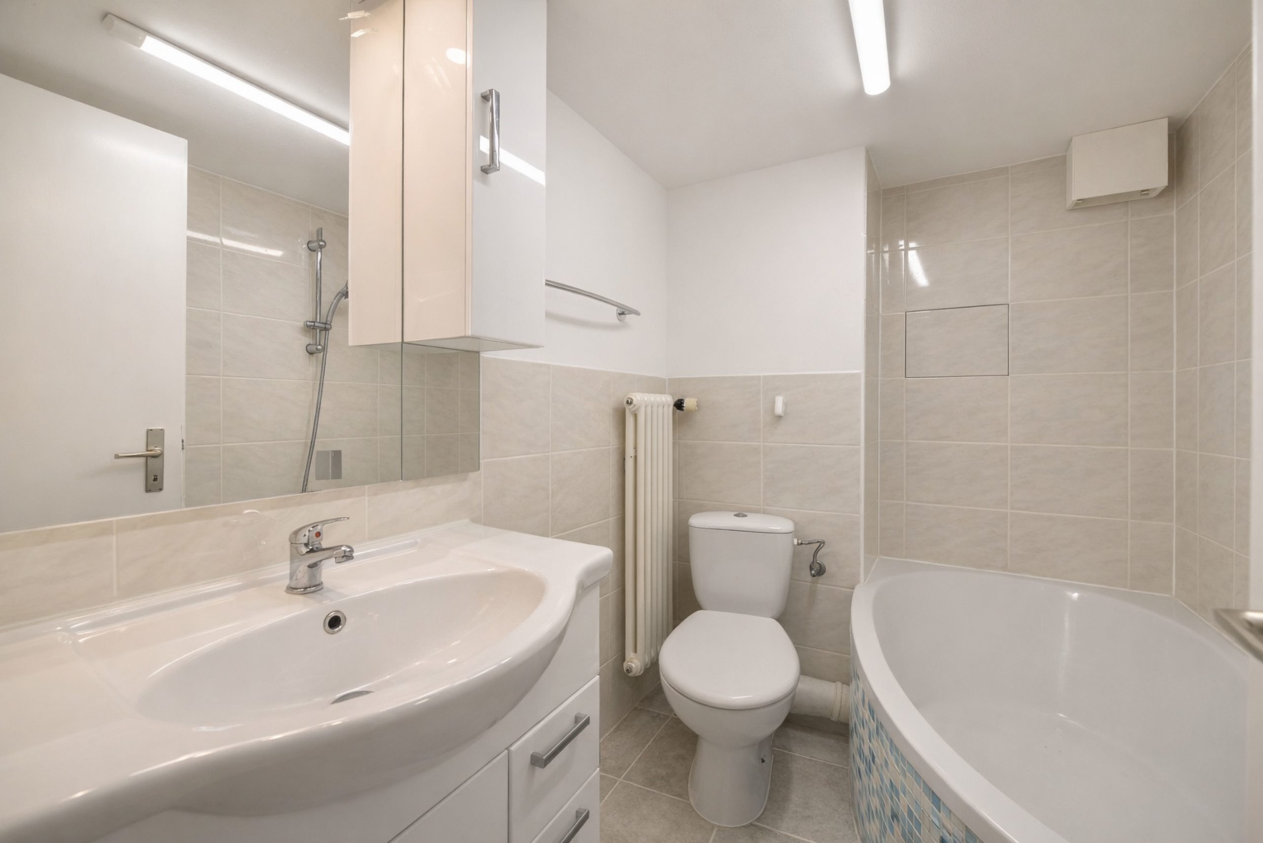 Helles, kompaktes Badezimmer mit Badewanne, WC und Waschtisch