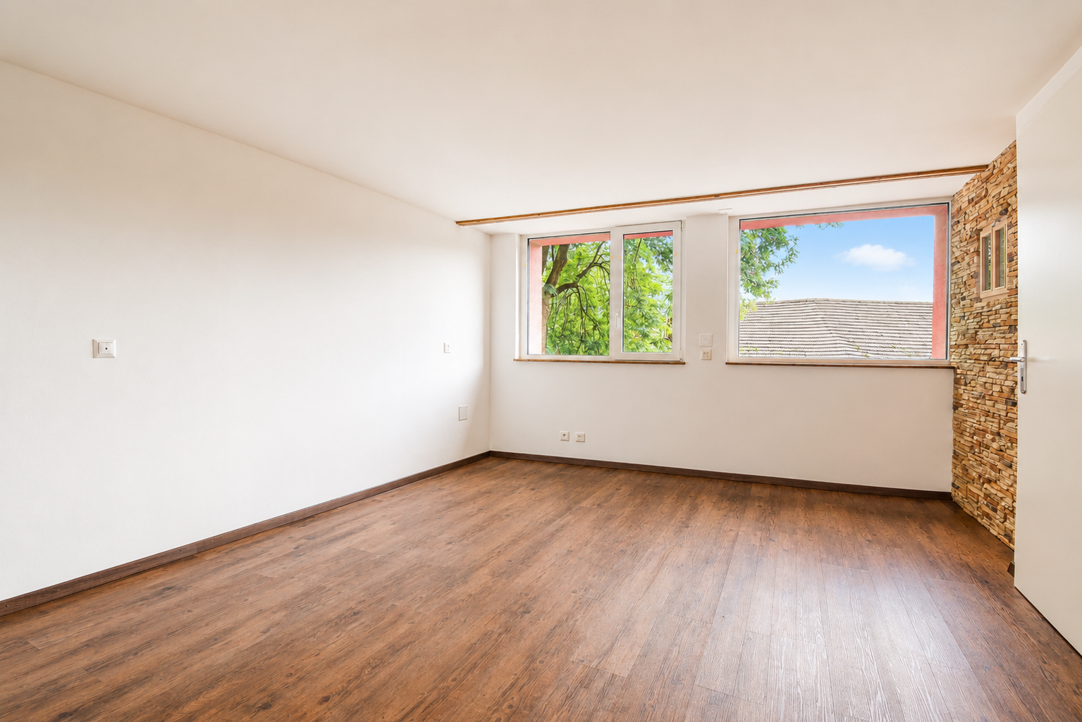 Heller leerer Raum mit Holzoptikboden und zwei Fenstern