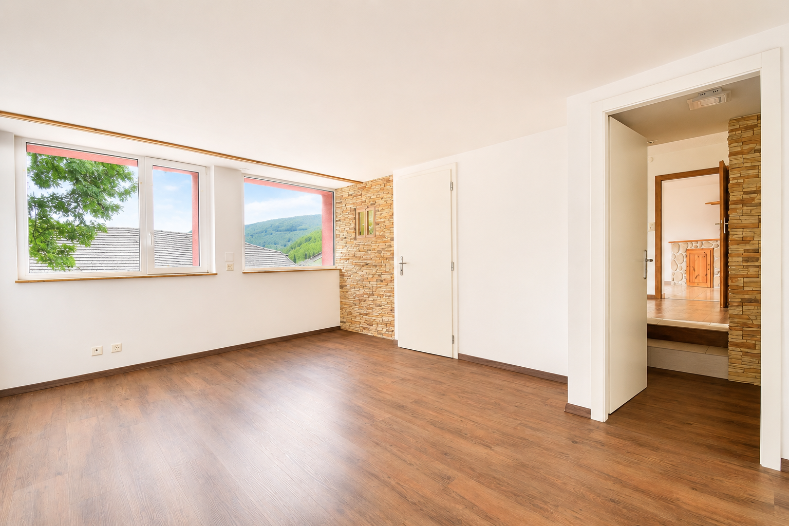 Helles, leeres Zimmer mit Holzfußboden und Blick ins Grüne