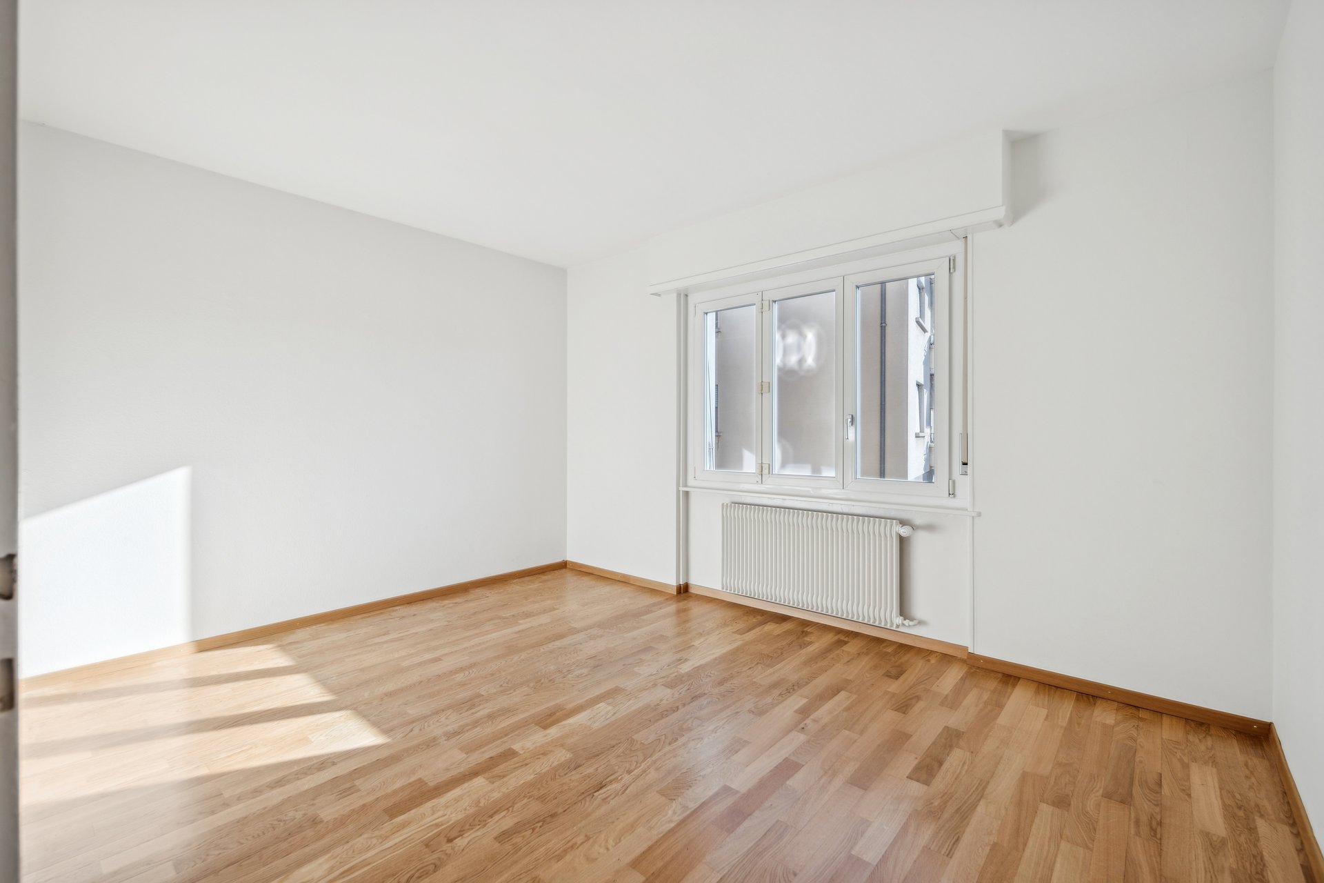 Heller leerer Raum mit Parkett und Fenster
