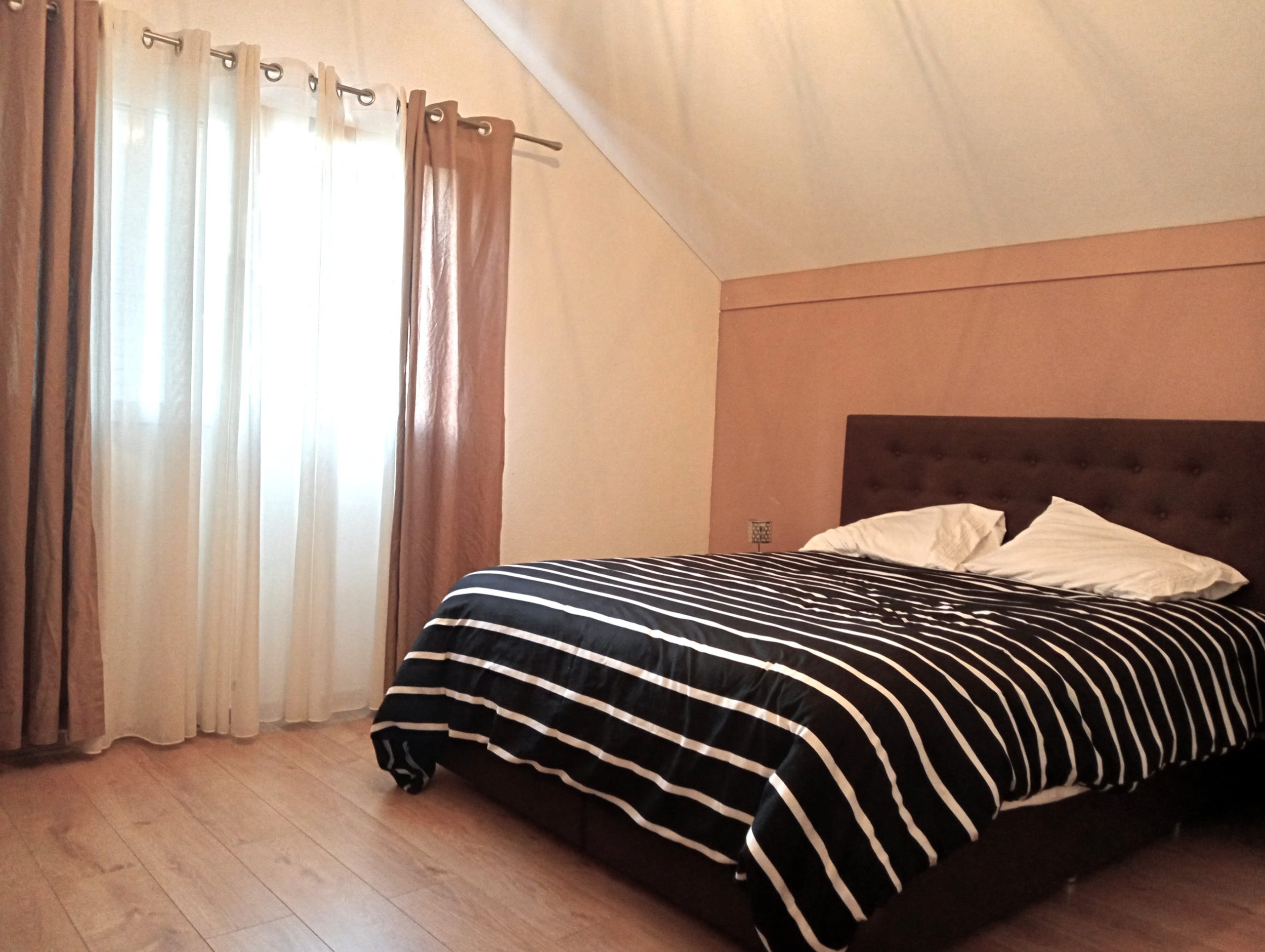Dachgeschoss-Schlafzimmer mit Bett und Fenstern