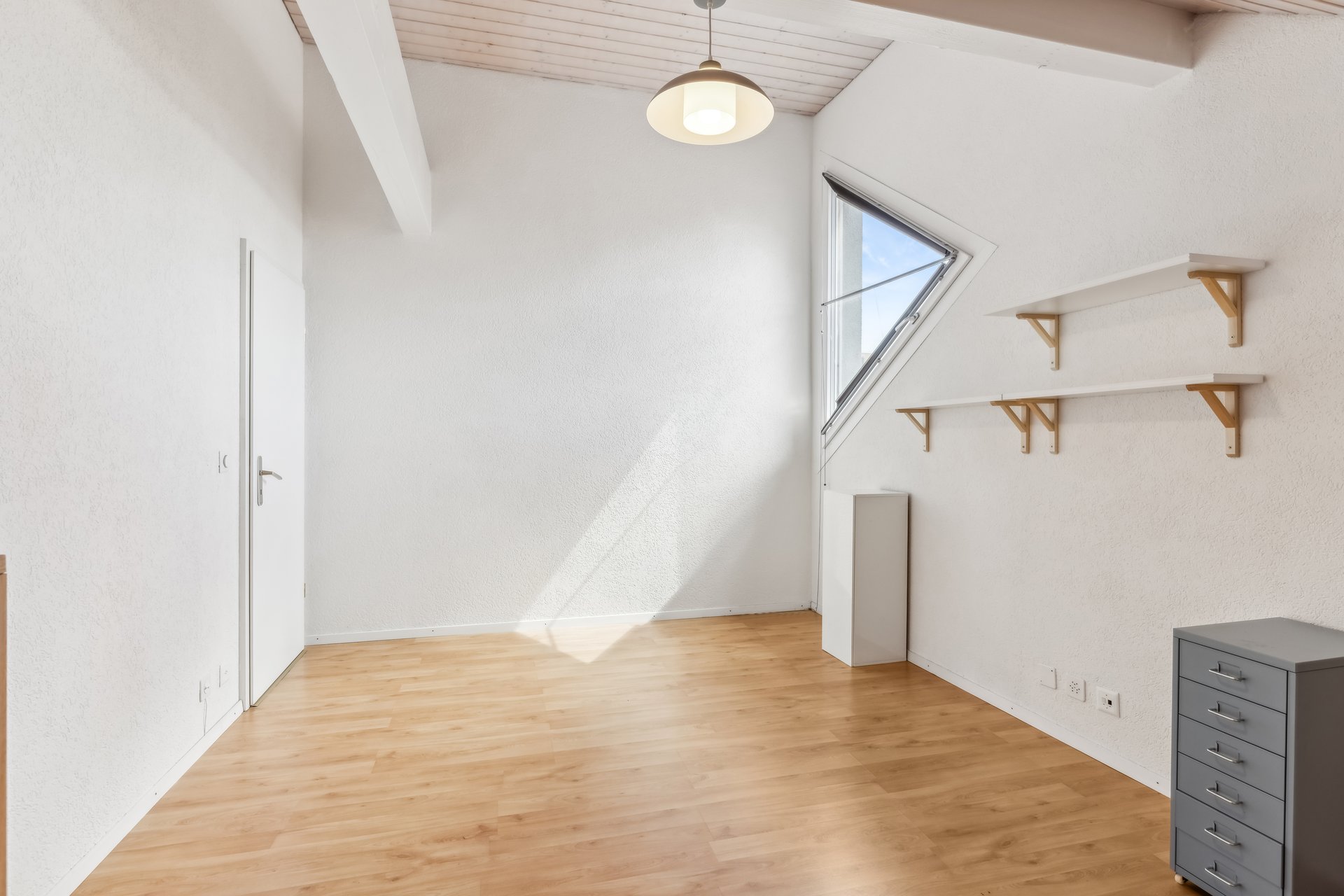 Helles, leeres Dachgeschosszimmer mit Fenster