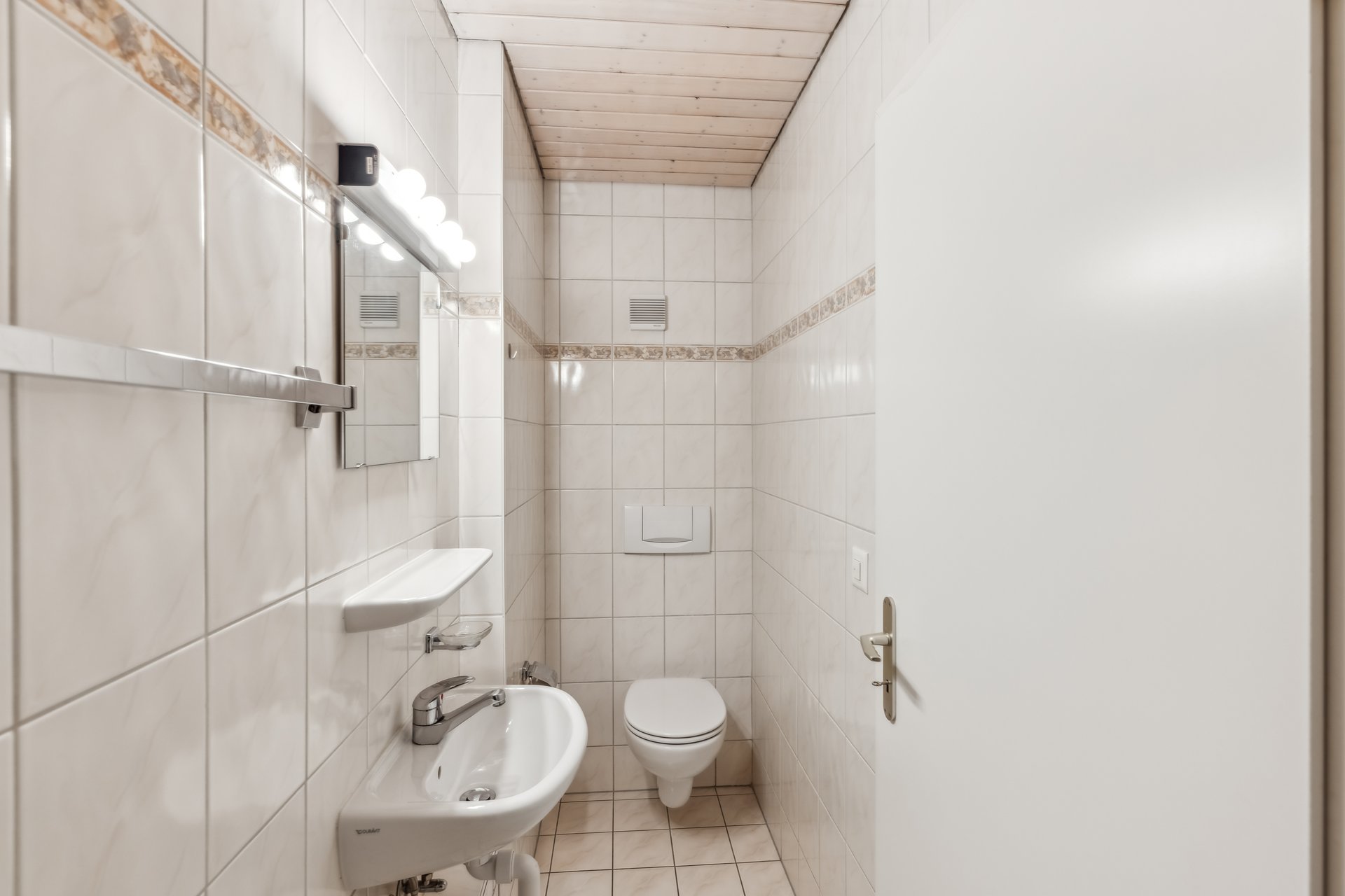 Kleines weiß gefliestes WC