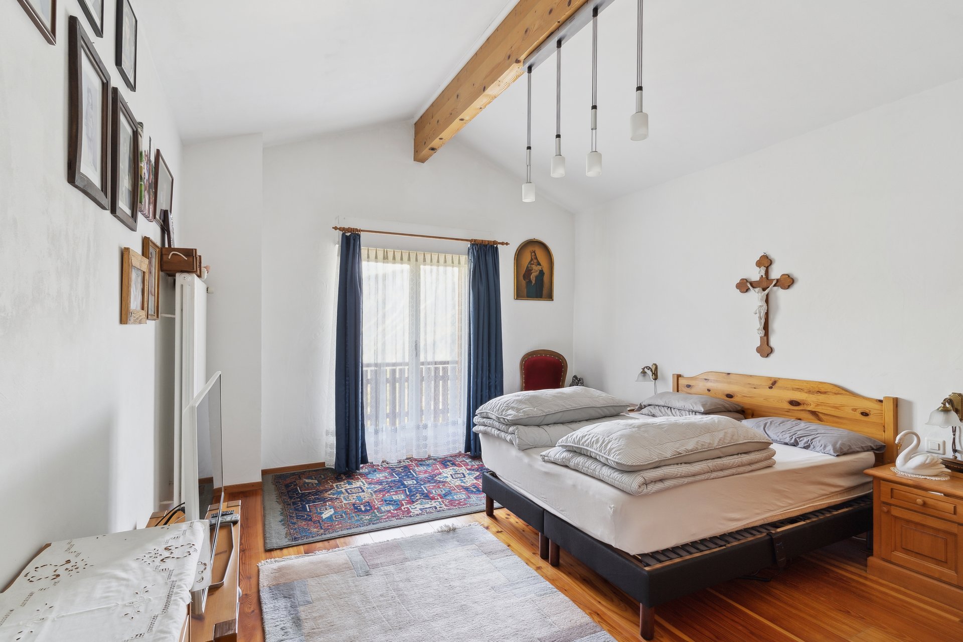 Helles Schlafzimmer mit Holzbalken und religiösen Wanddekorationen