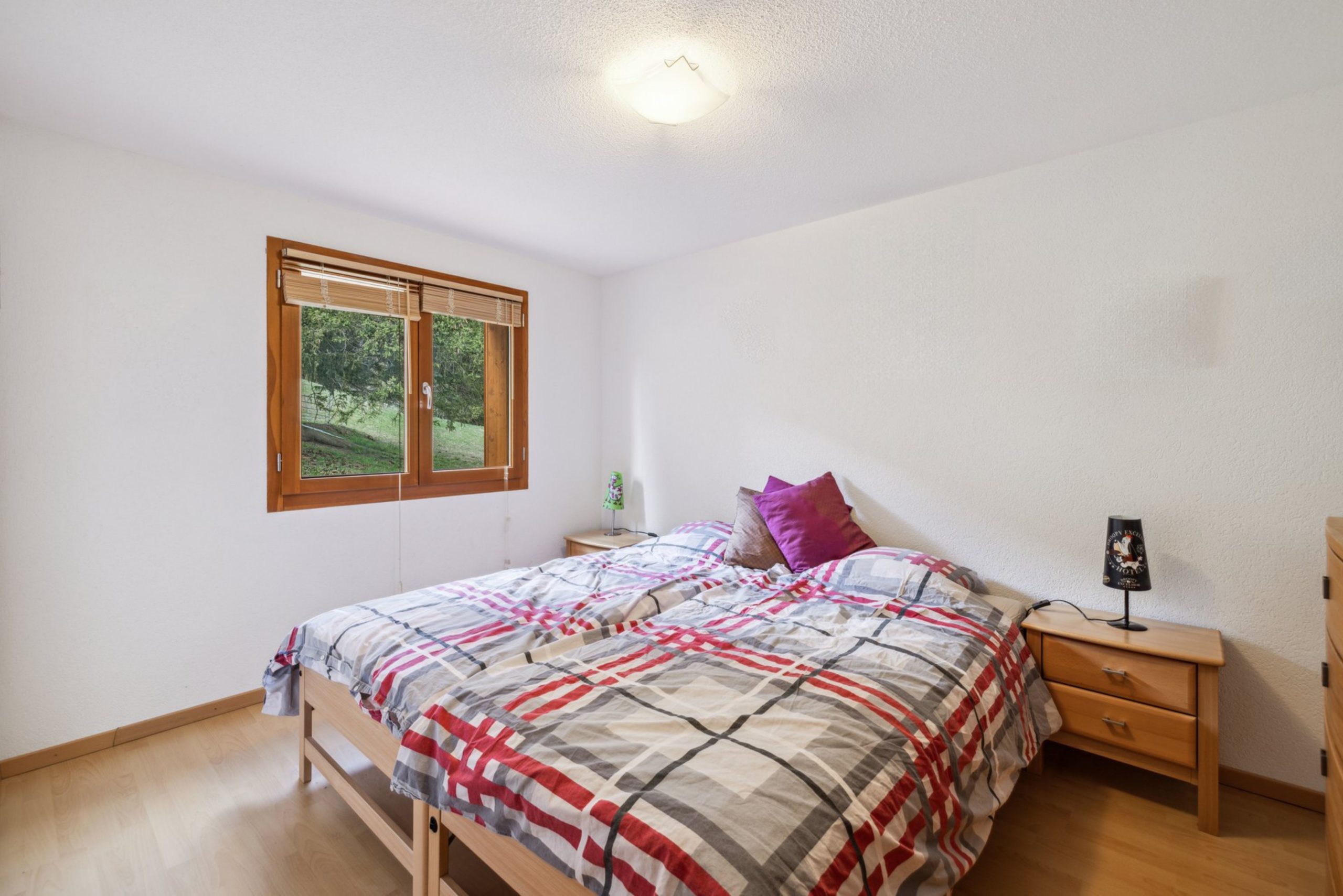 Helles Schlafzimmer mit Doppelbett und Holzfenster
