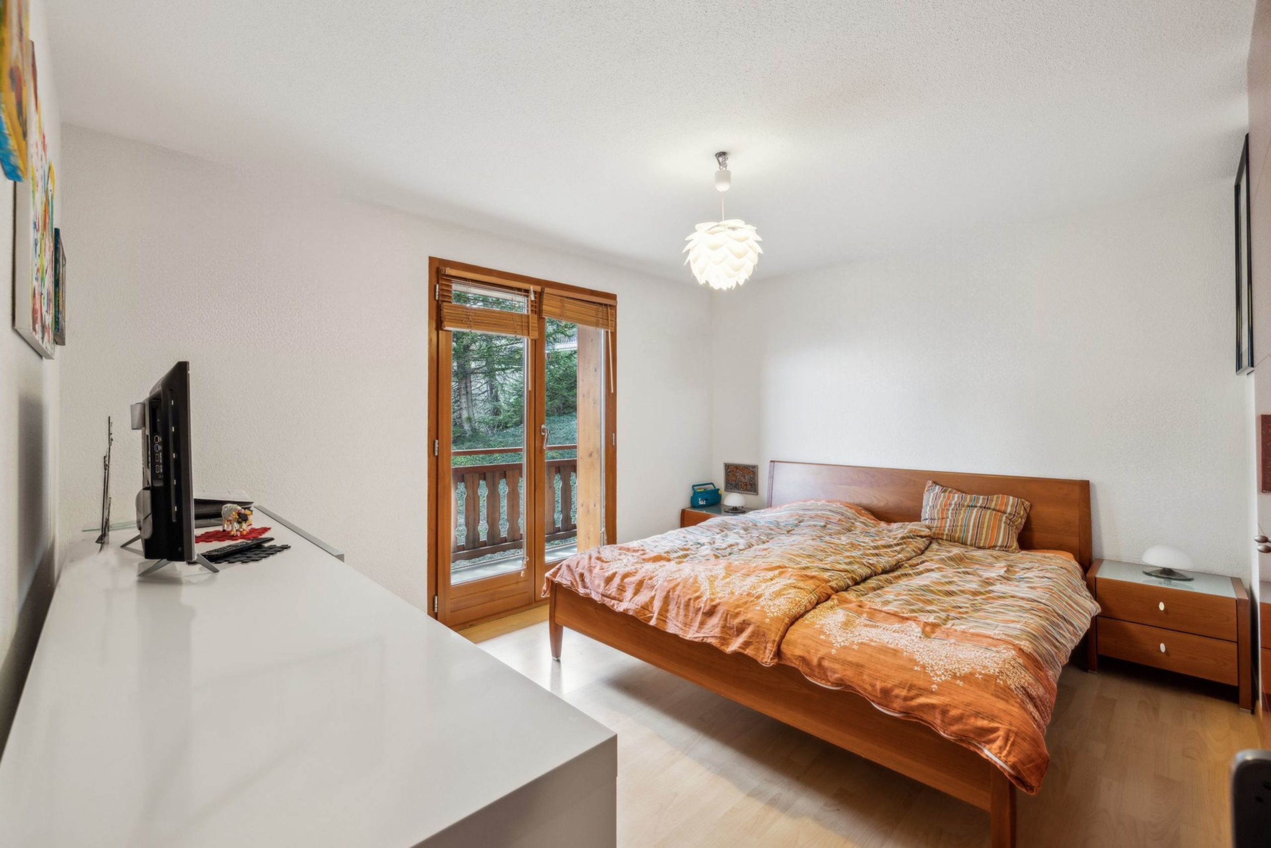 Helles Schlafzimmer mit Holzdetails und Balkonzugang