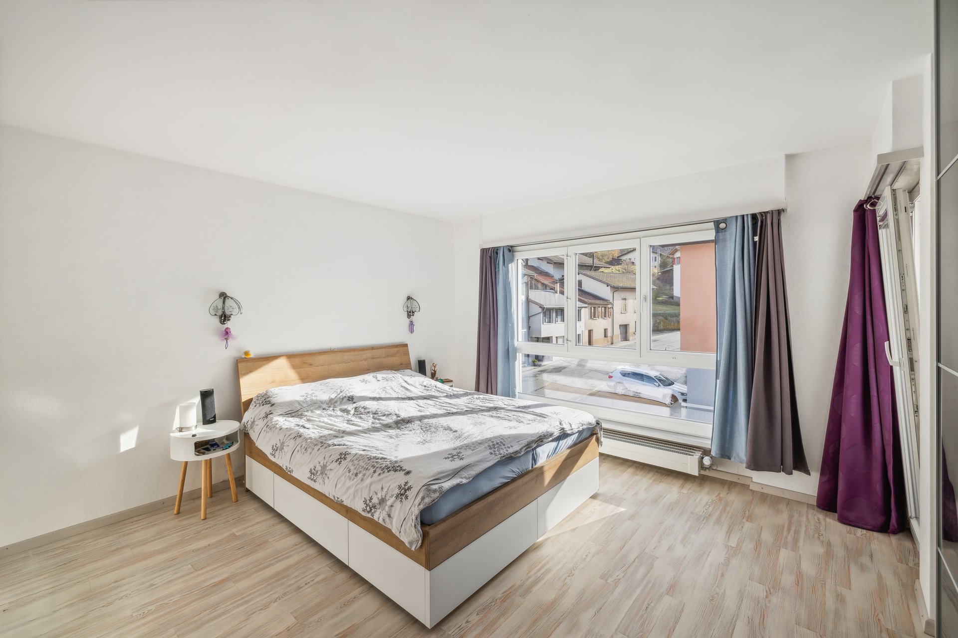 Helles Schlafzimmer mit großem Fenster und Doppelbett
